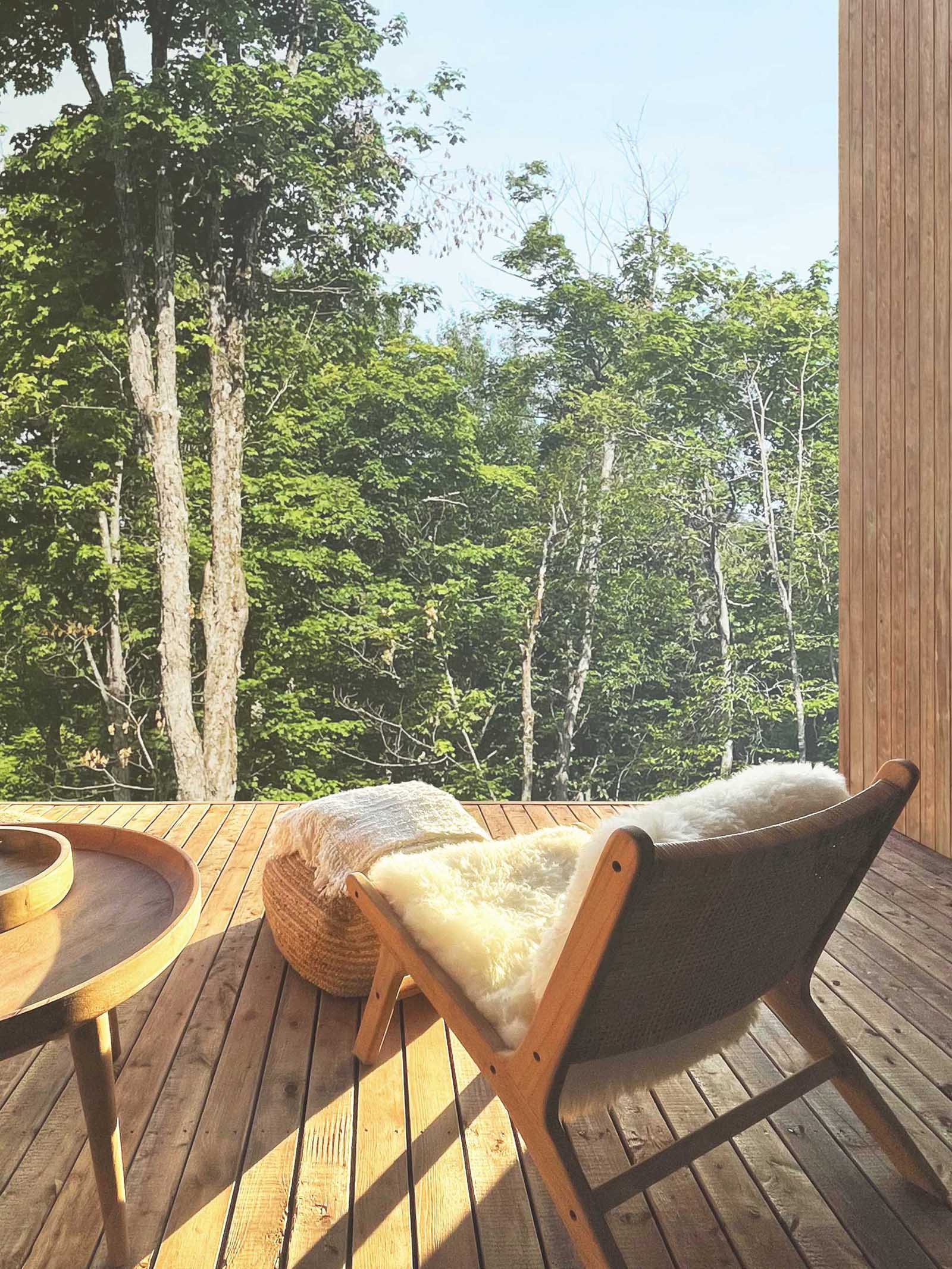 A modern house with a deck furnished with a pair of chairs.