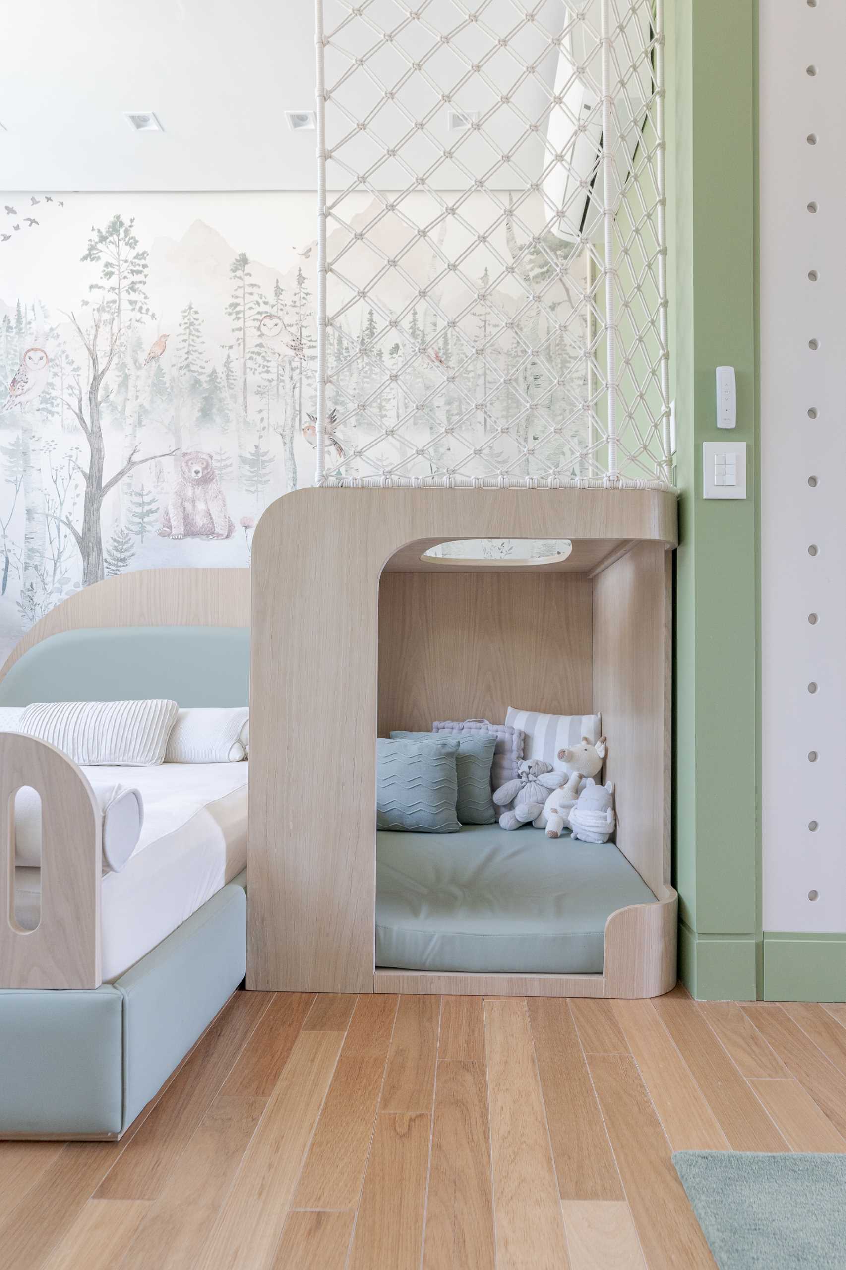 In this modern kid's bedroom, there's a woodland mural on the wall, a small reading nook, a pegboard wall, and storage cabinet for toys.