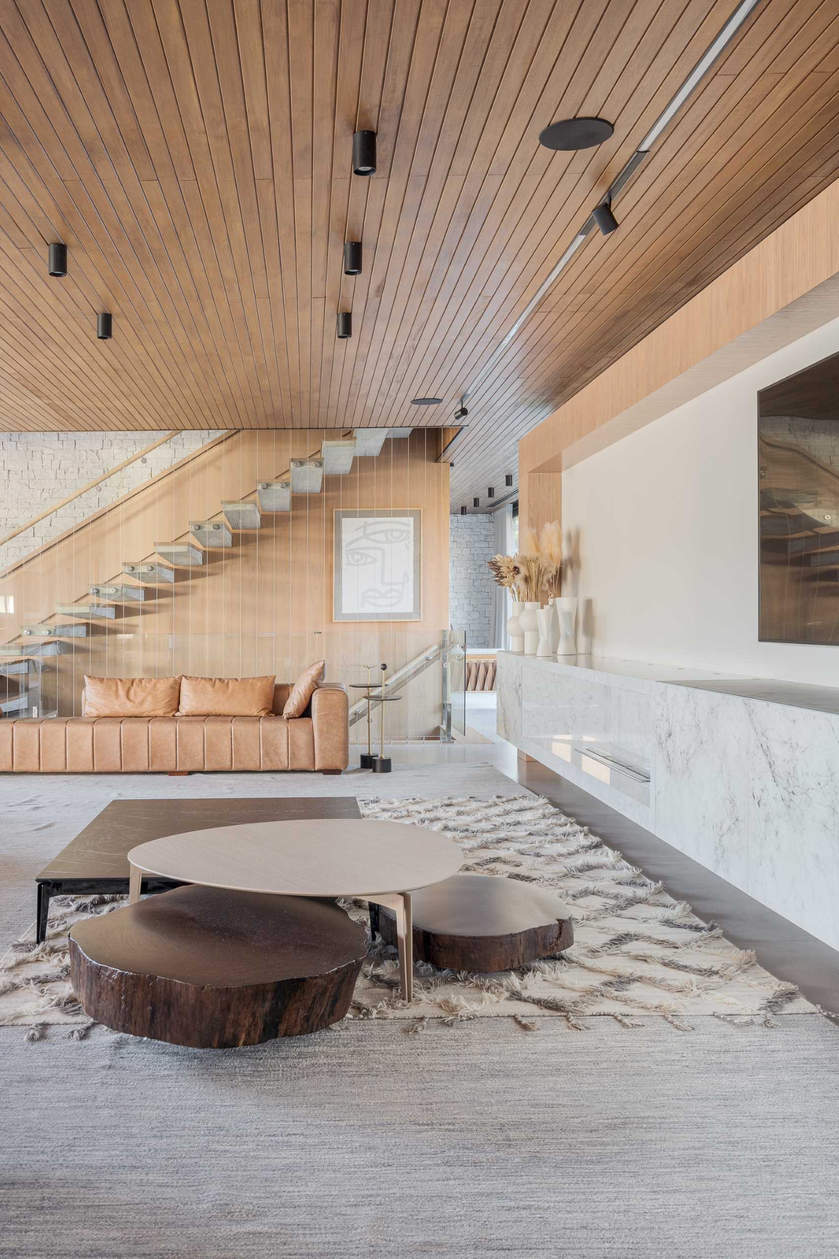 A wood ceiling is showcased throughout the home, while the living room includes an L-shaped couch as well as a secondary couch by the stairs.