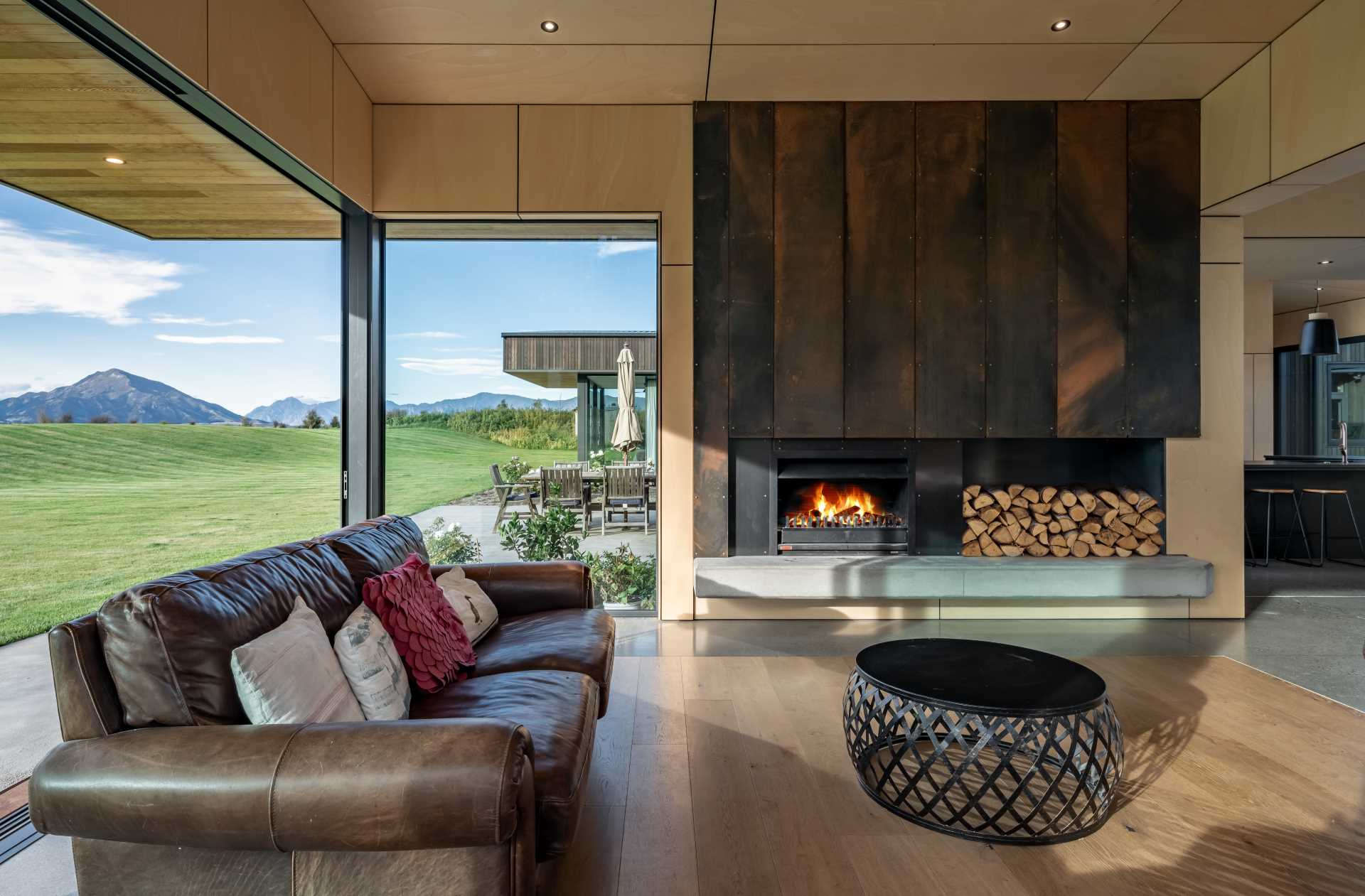 In this modern living room, a feature wall of waxed Corten steel lends a striking focal point that references the exterior materiality.