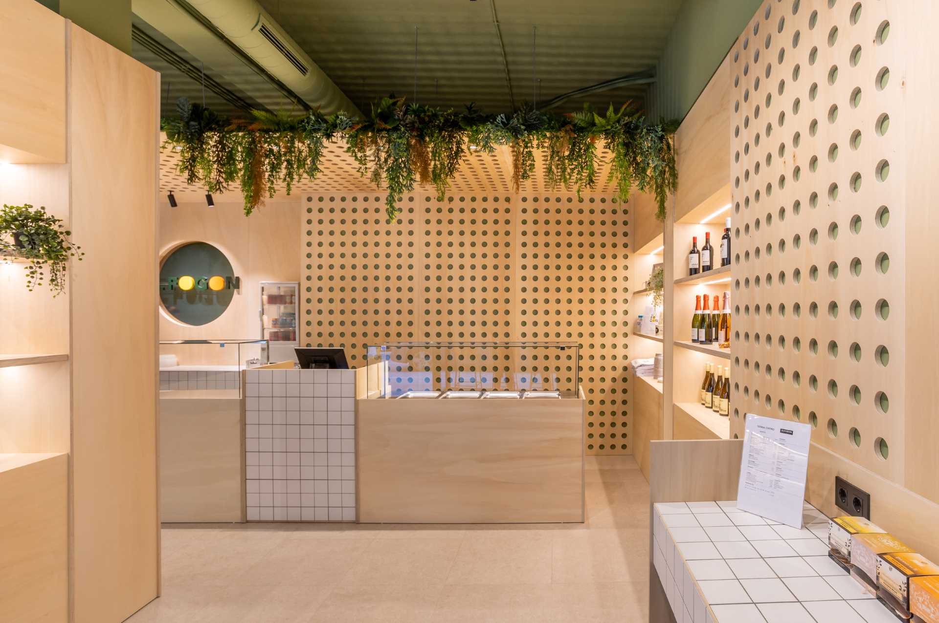 A modern takeaway shop with perforated wood panels, LED lighting, white square tiles, and plants.