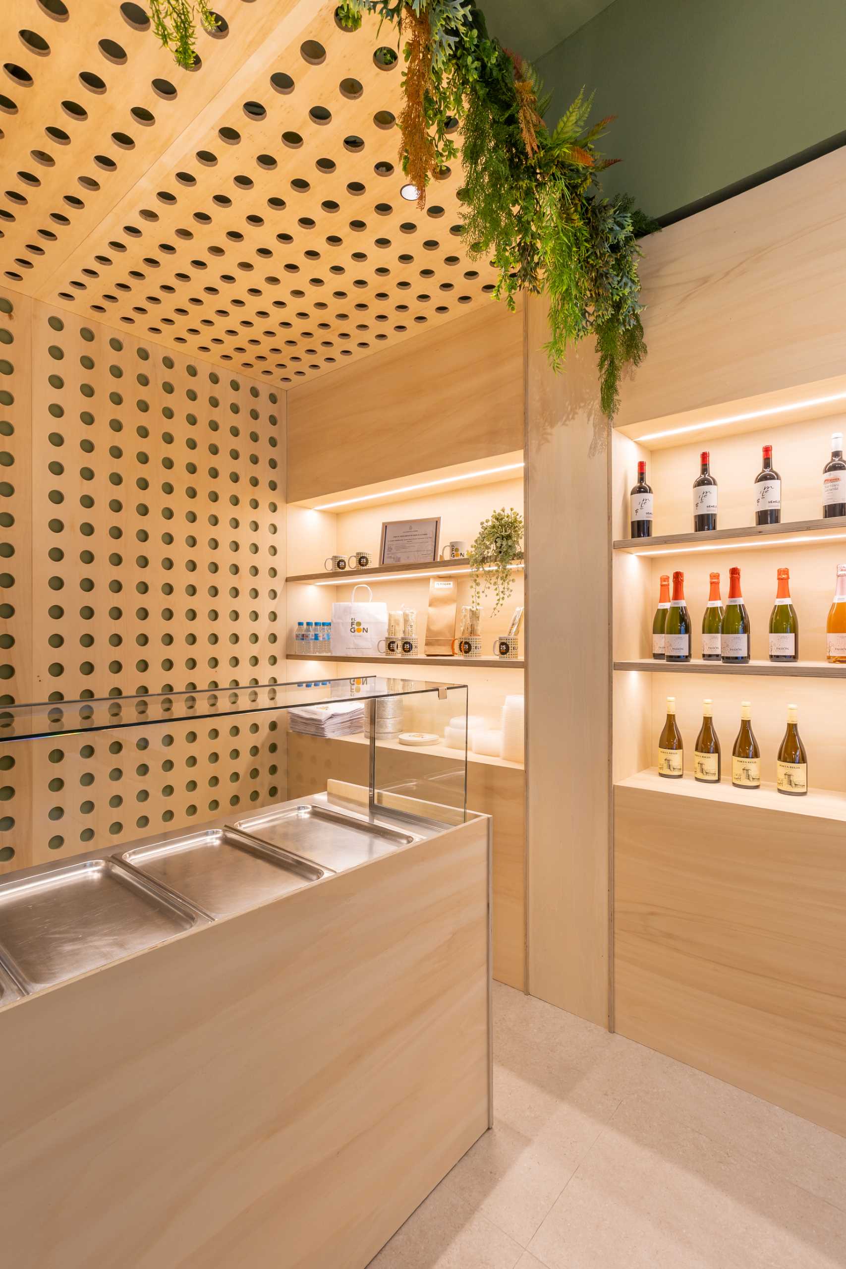 A modern takeaway shop with perforated wood panels, plants, and shelving with LED lighting.