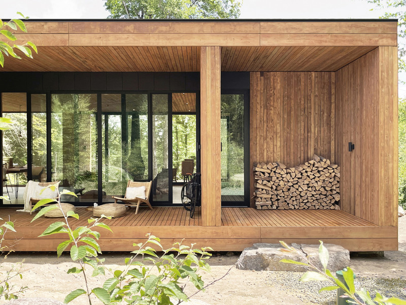 This modern house, comprised of several glass frames surrounded by wood, is perched on the side of the mountain and faces the treetops.