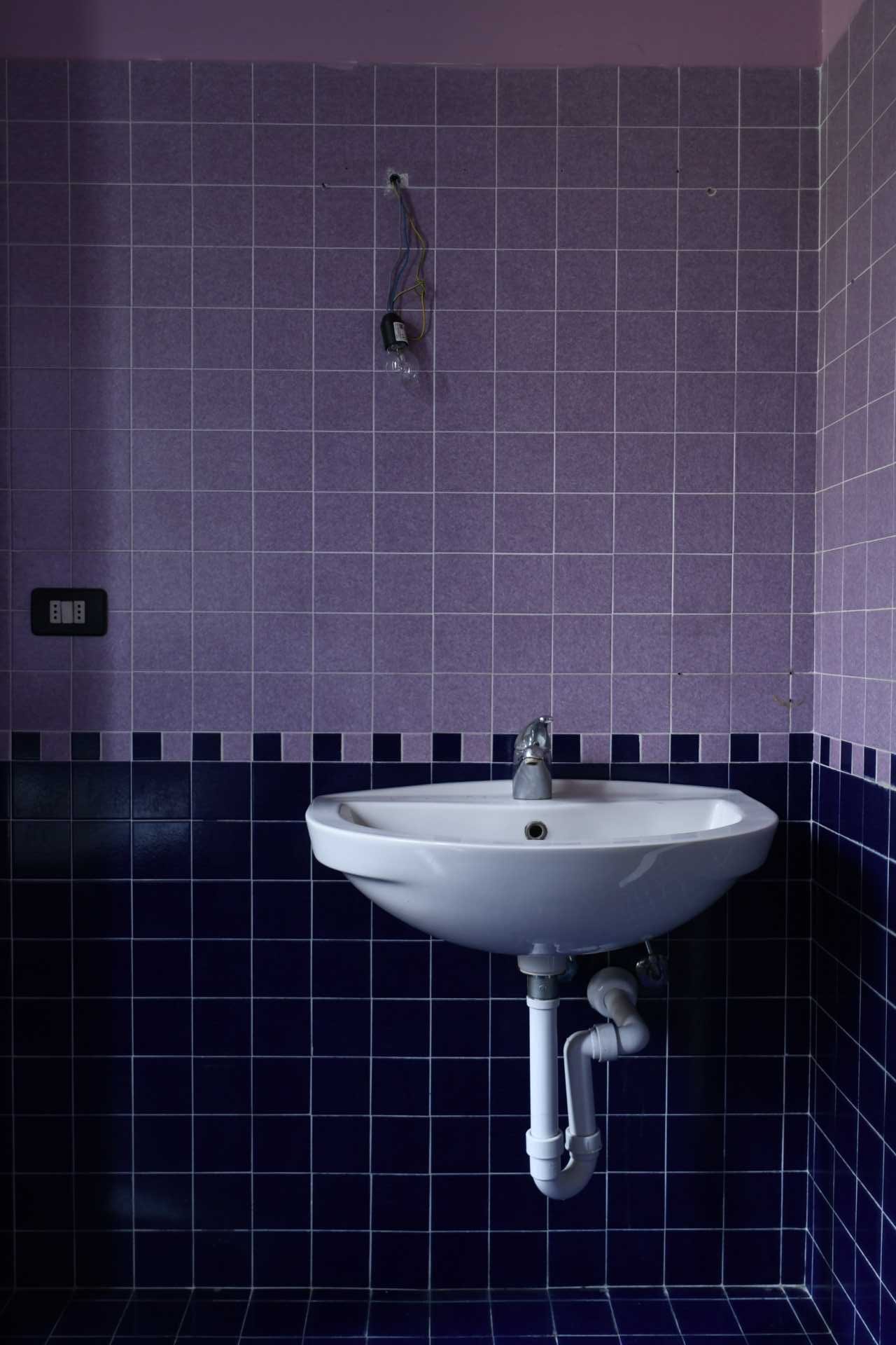 Before photo of a purple-tiled bathroom.