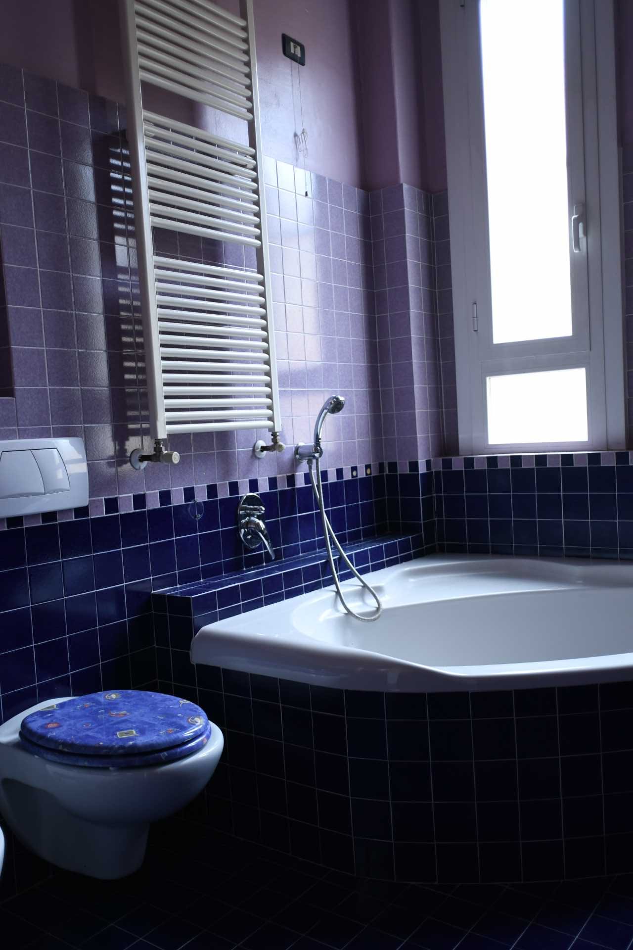 Before photo of a purple-tiled bathroom.