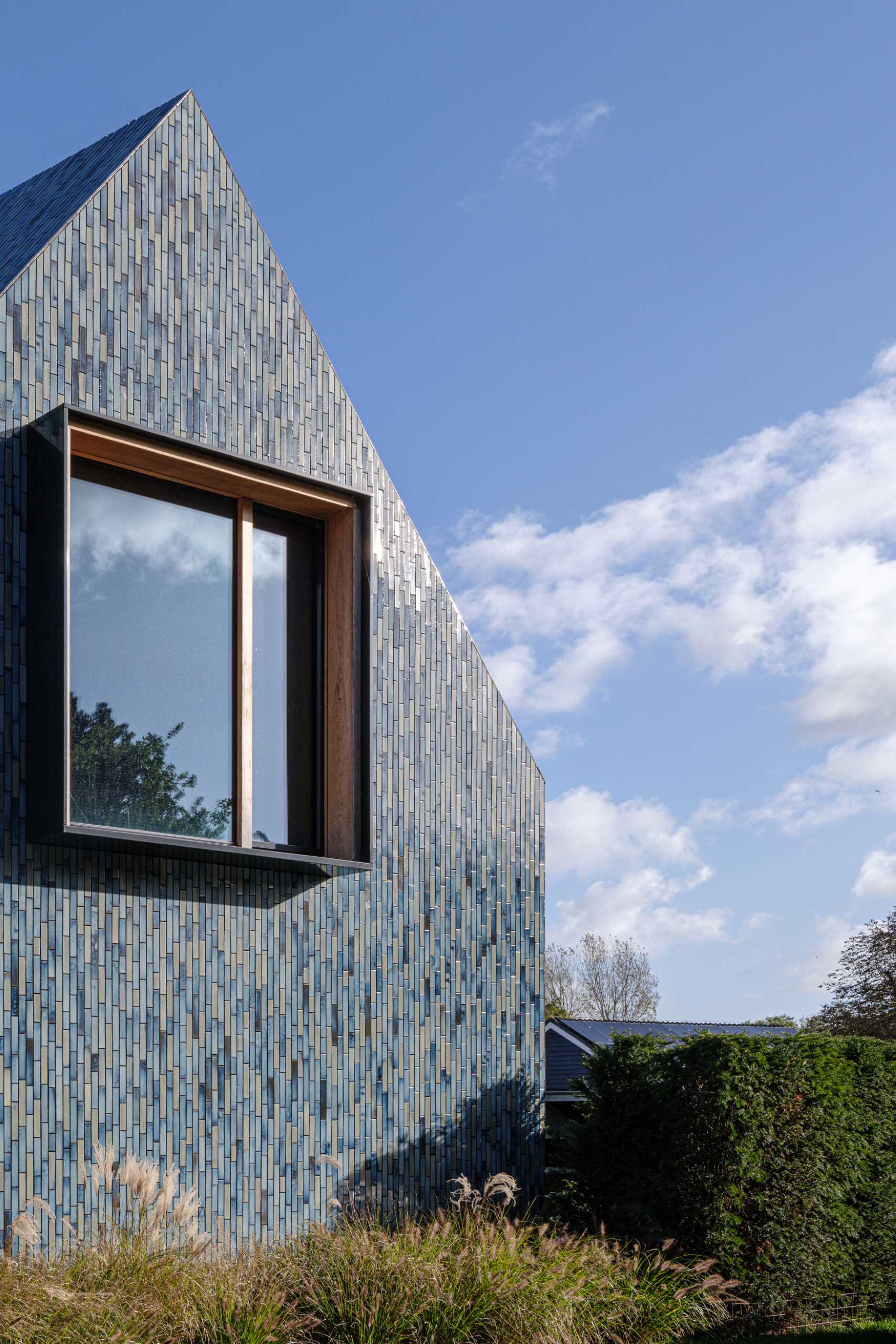 A modern house covered in blue tiles, that also has a twisted roof.