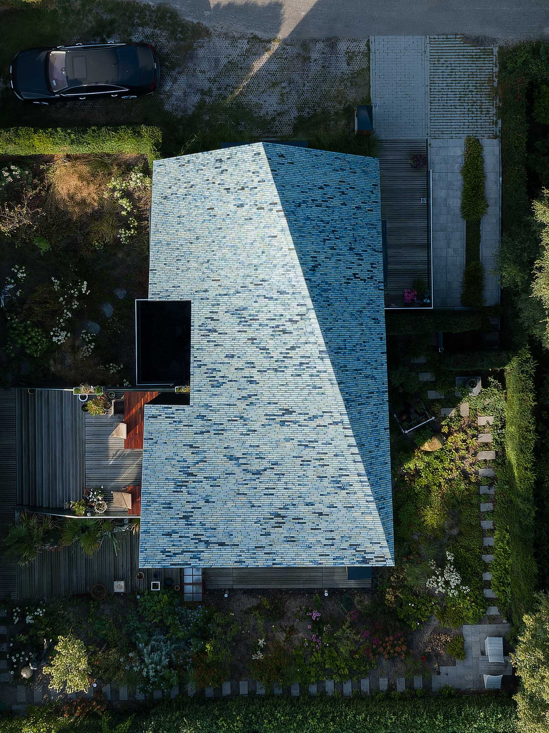 A modern house covered in blue tiles, that also has a twisted roof.