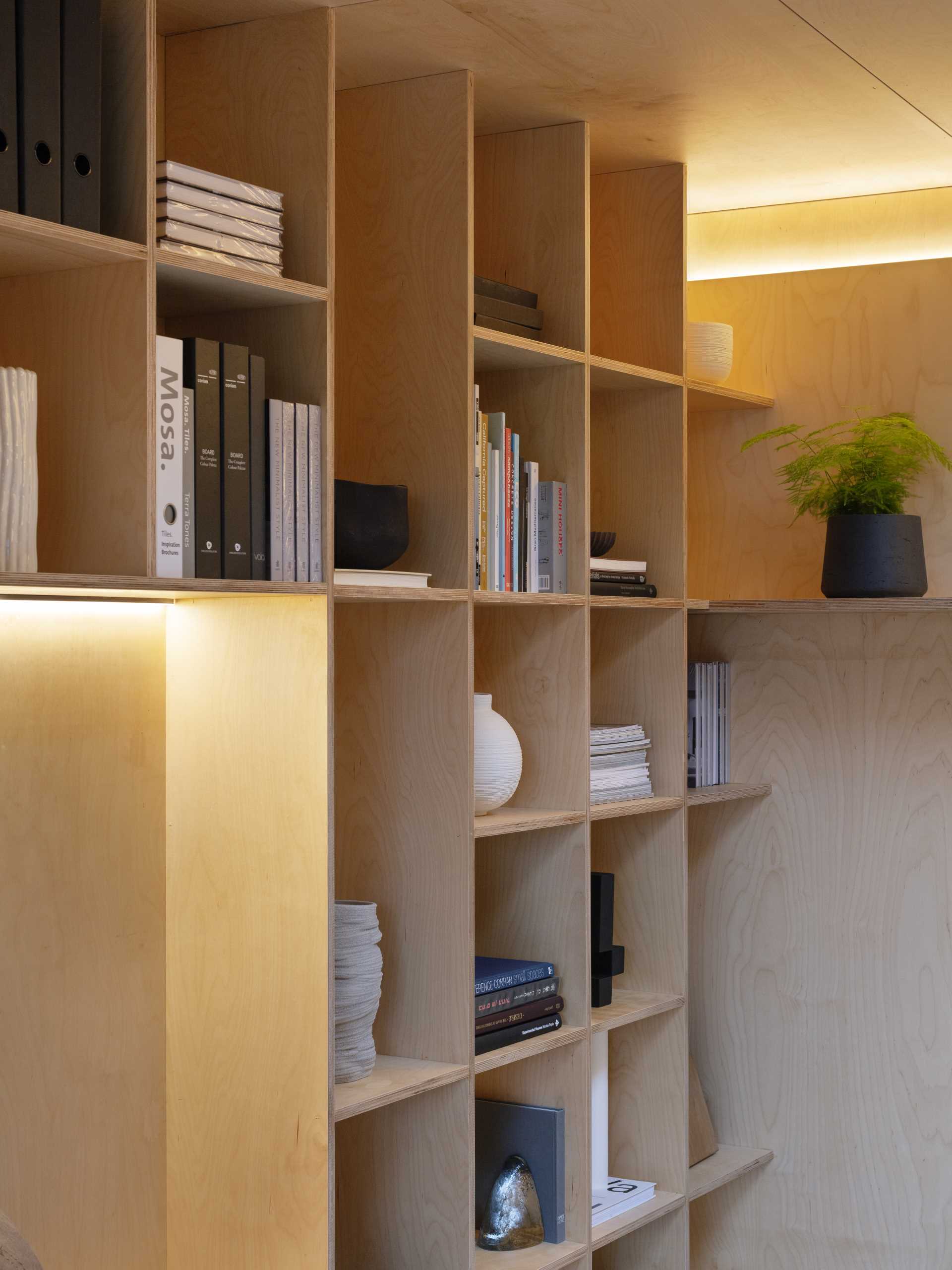 A wall of plywood bookshelves and hidden lighting.