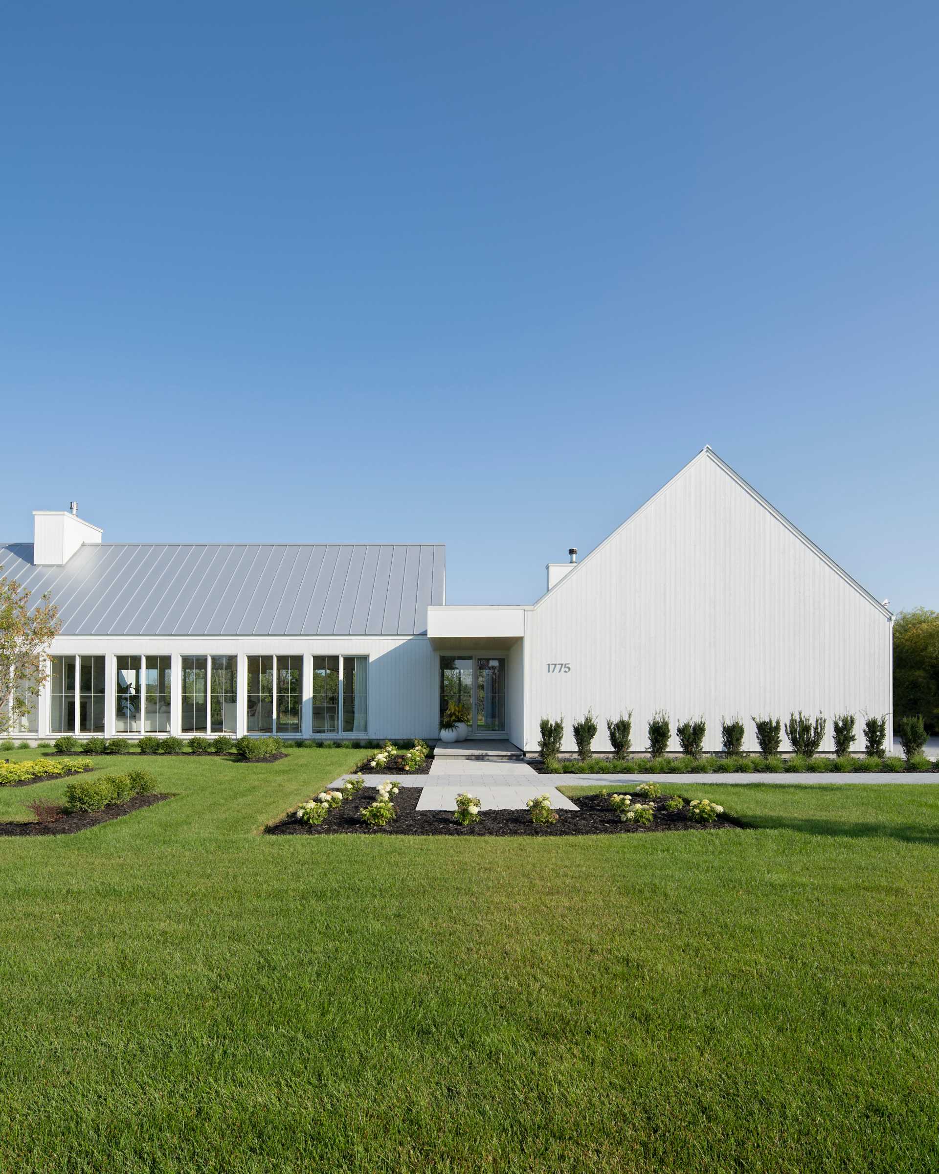 A contemporary house with a white exterior and landscaped yard.