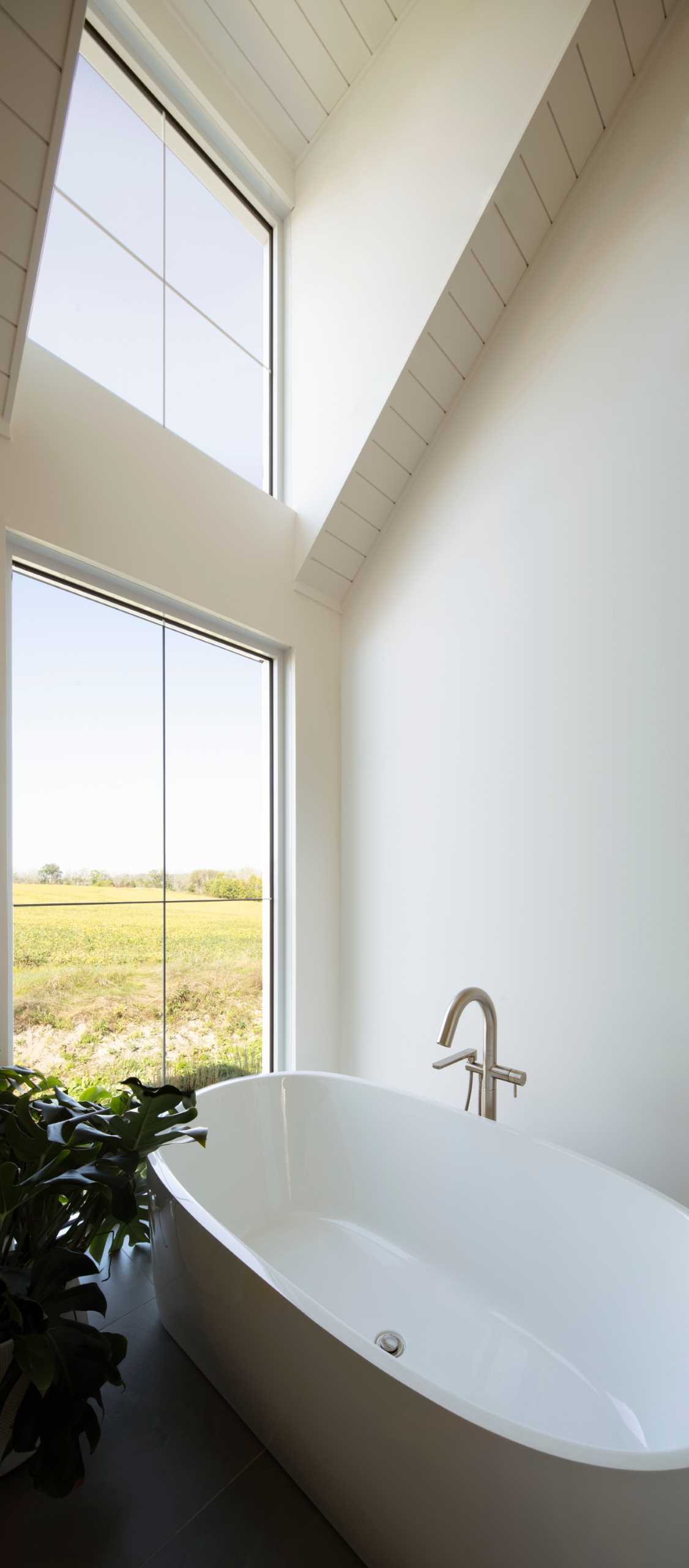 Phòng tắm hiện đại với bồn tắm đứng cạnh cửa sổ.