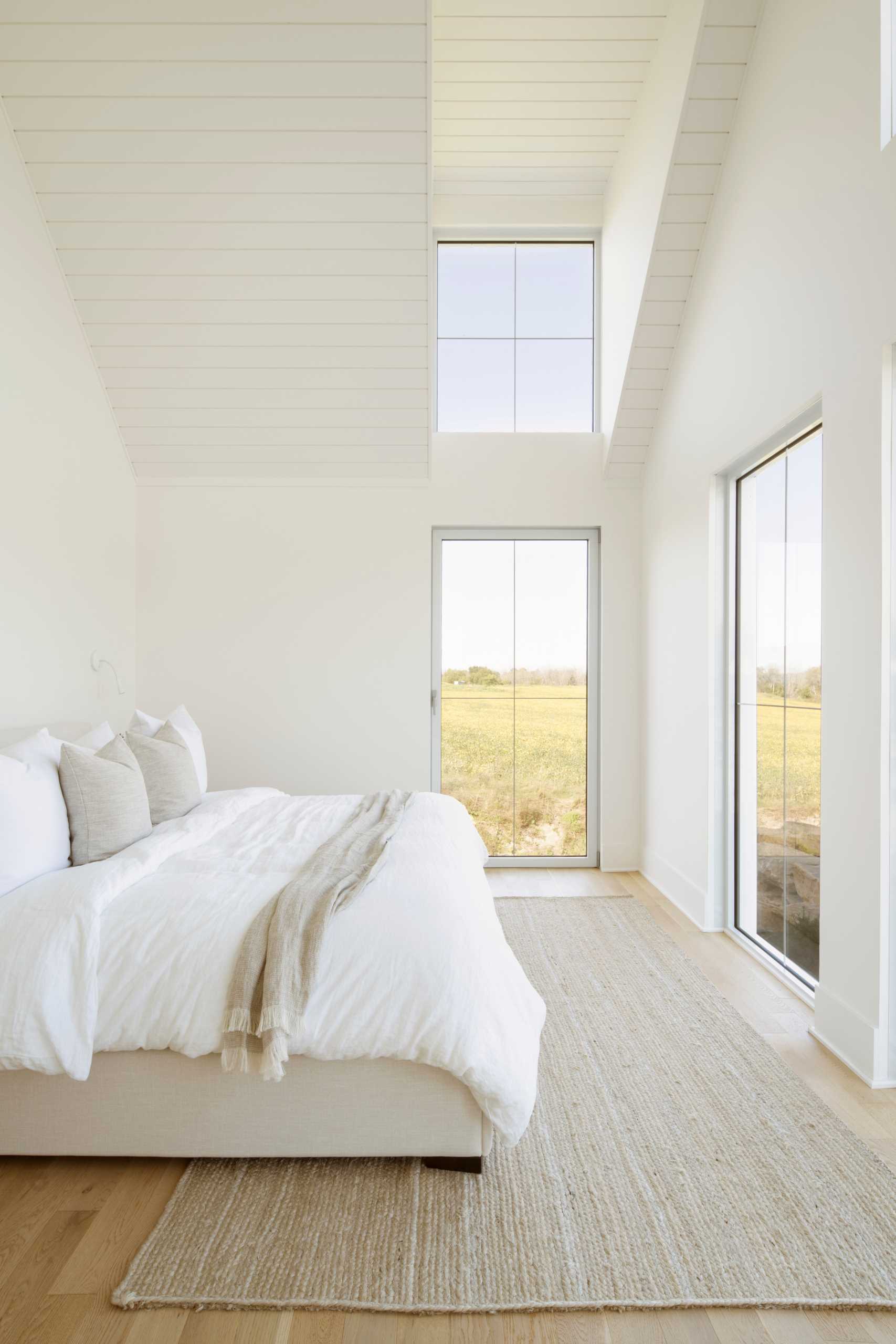 A contemporary bedroom with windows that look out to the landscape.