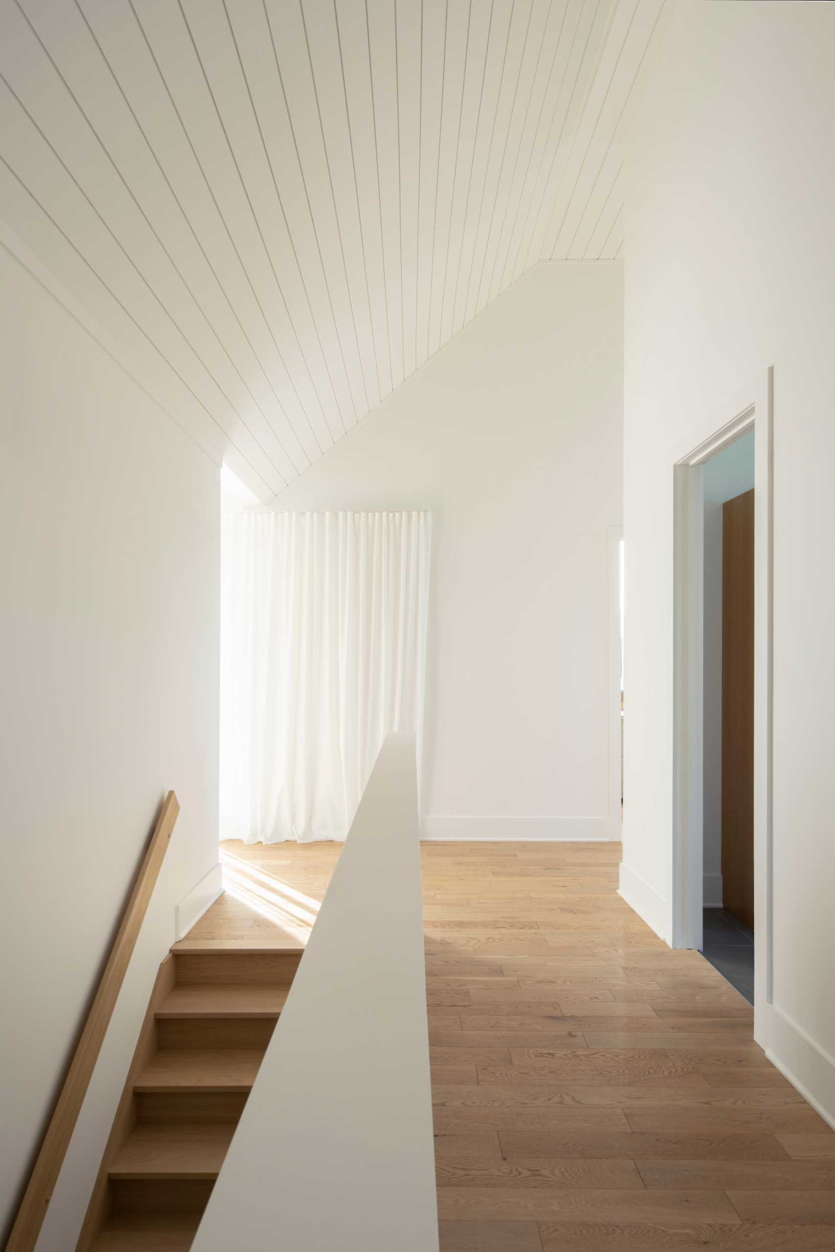 A contemporary house with a white interior and wood floors.