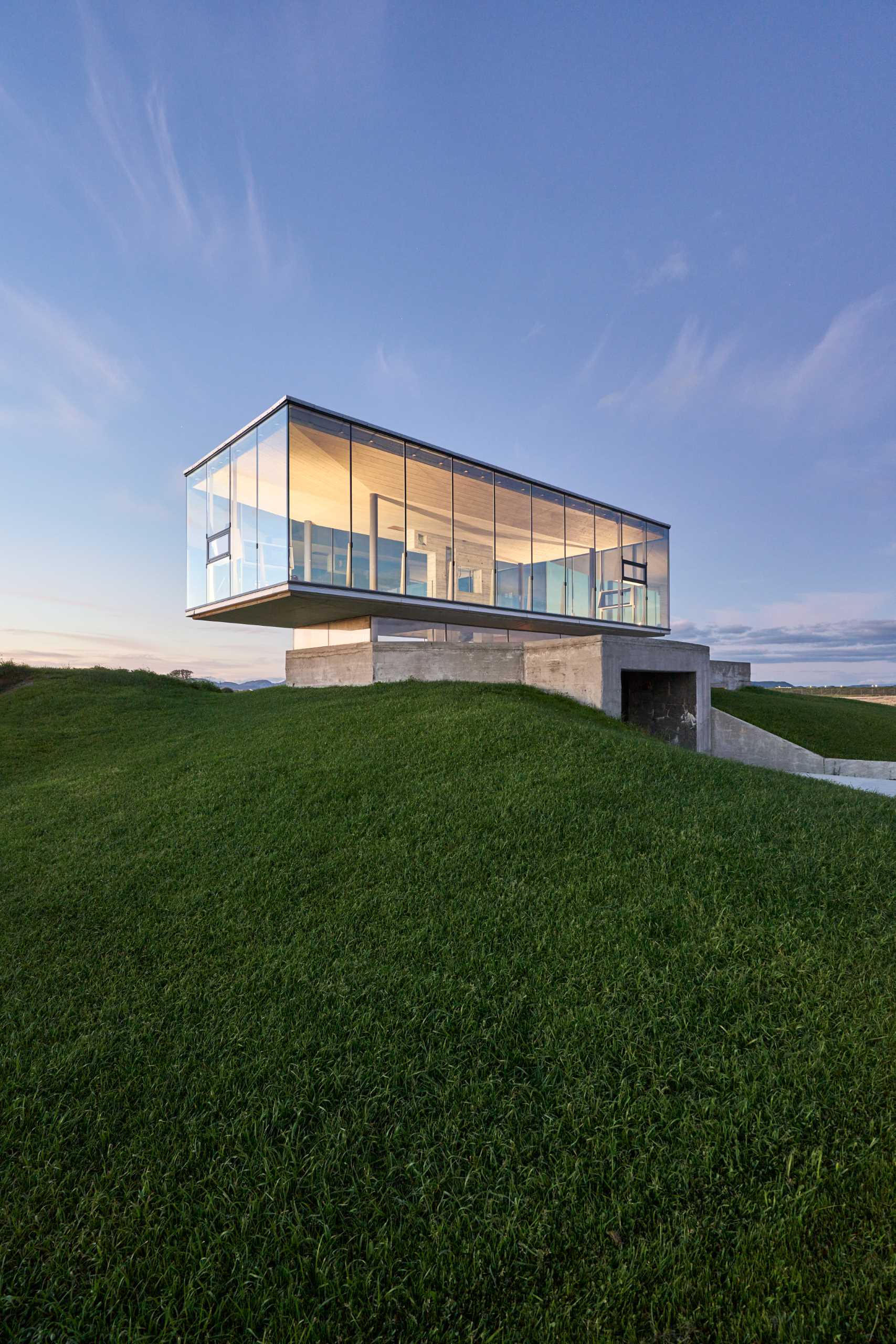 An old military bunker has been transformed into an event space with a glass-enclosed box.