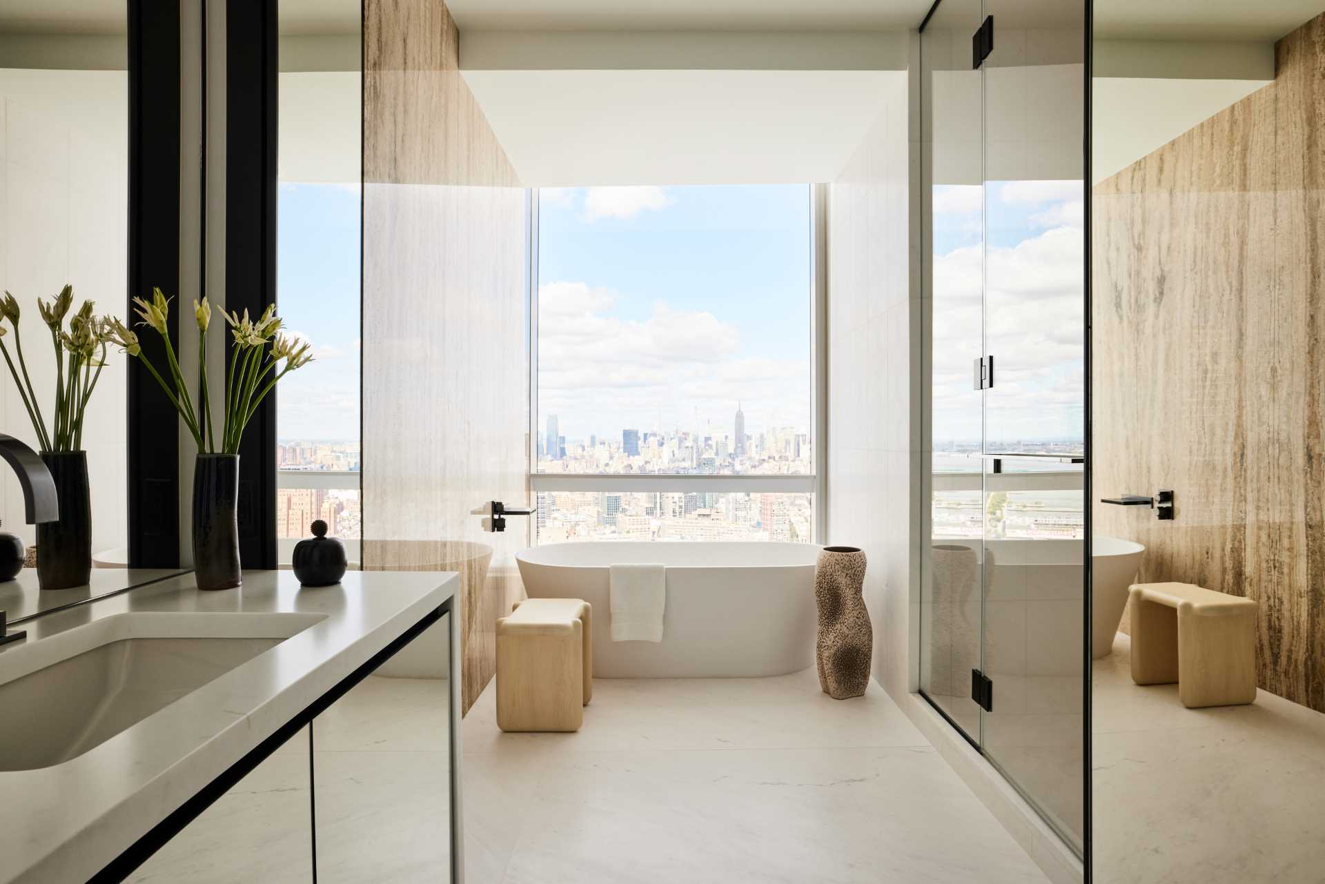 In this modern bathroom, a freestanding bathtub is positioned in front of a window that perfectly frames the city views.