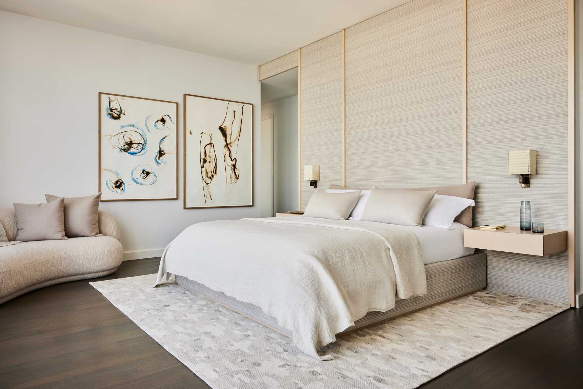 A modern bedroom with a neutral color palette and small sitting area.