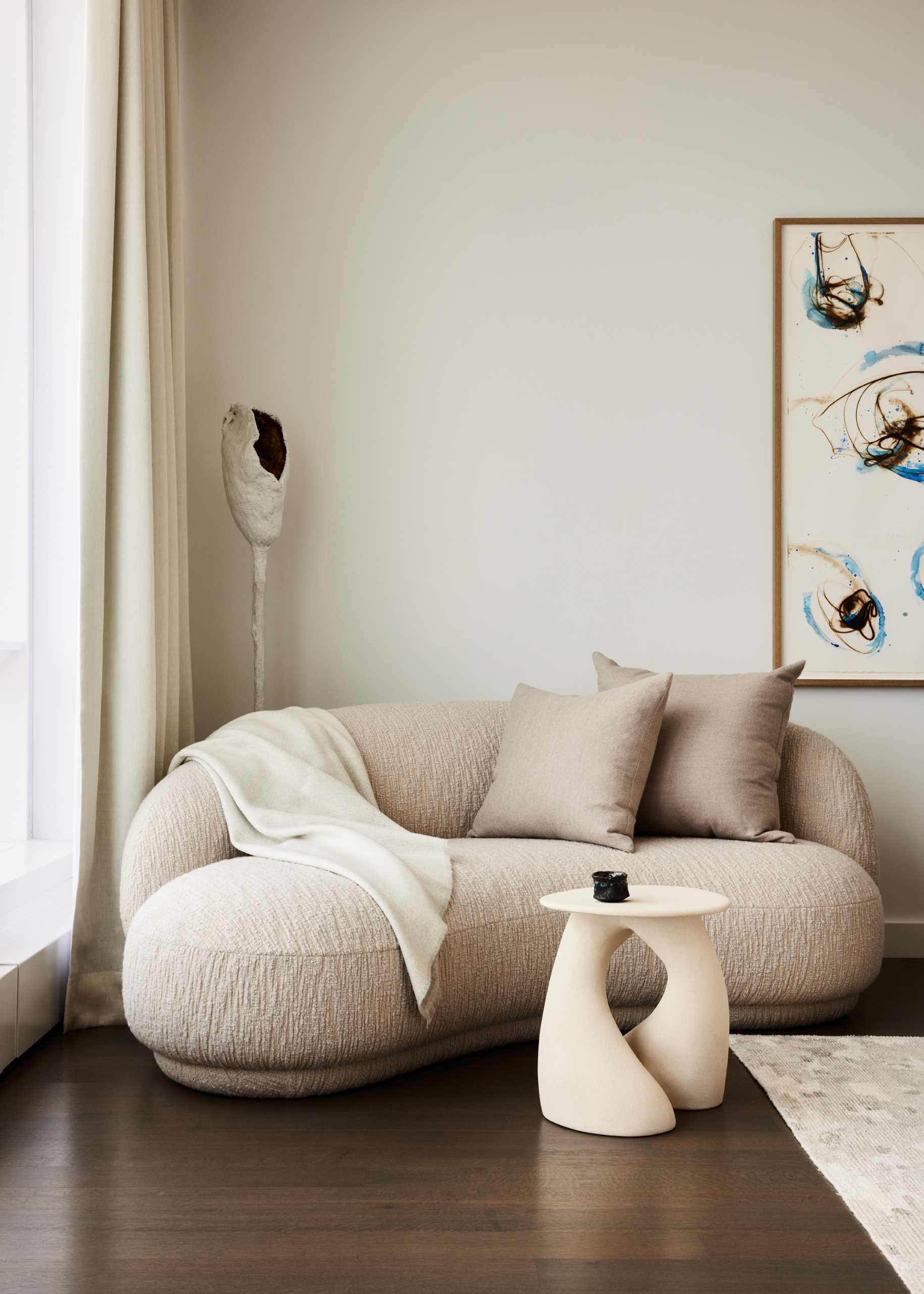 A modern bedroom with a neutral color palette and small sitting area.