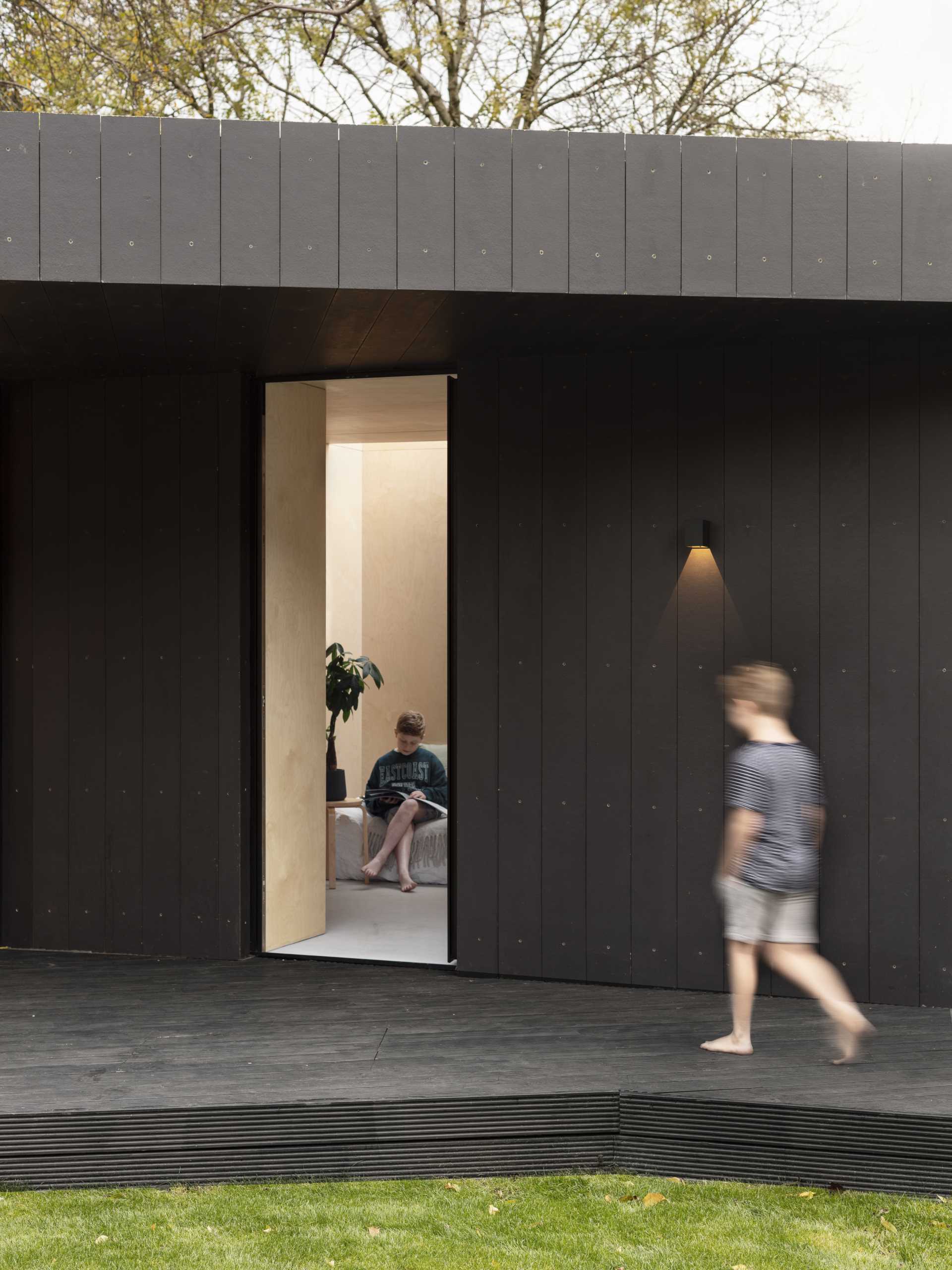 A backyard studio and guest suite has been built with blockwork walls, a timber structure roof, and black fibre-cement cladding.