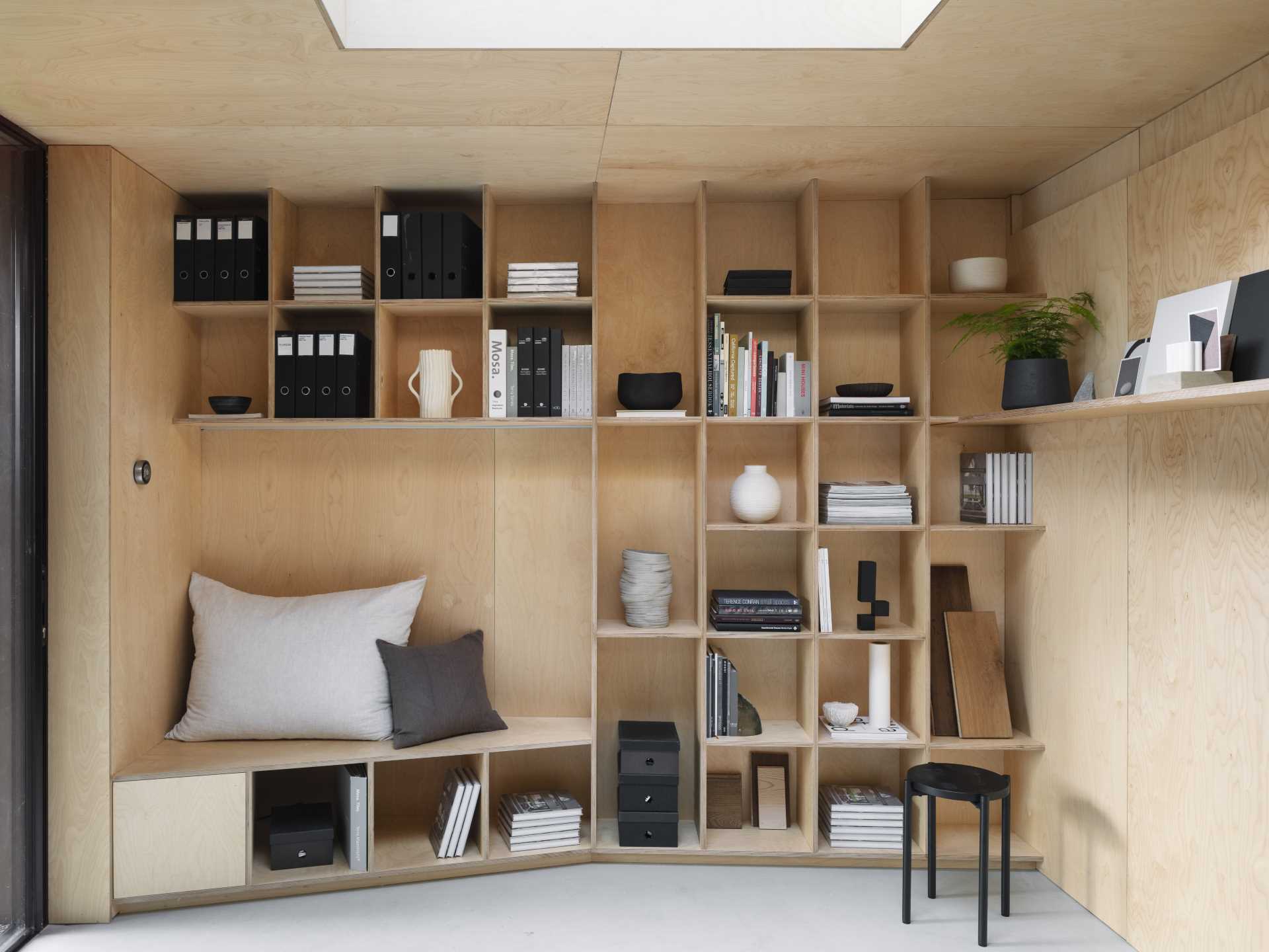 A backyard studio designed as an office includes a wall of bookshelves and a seating nook.