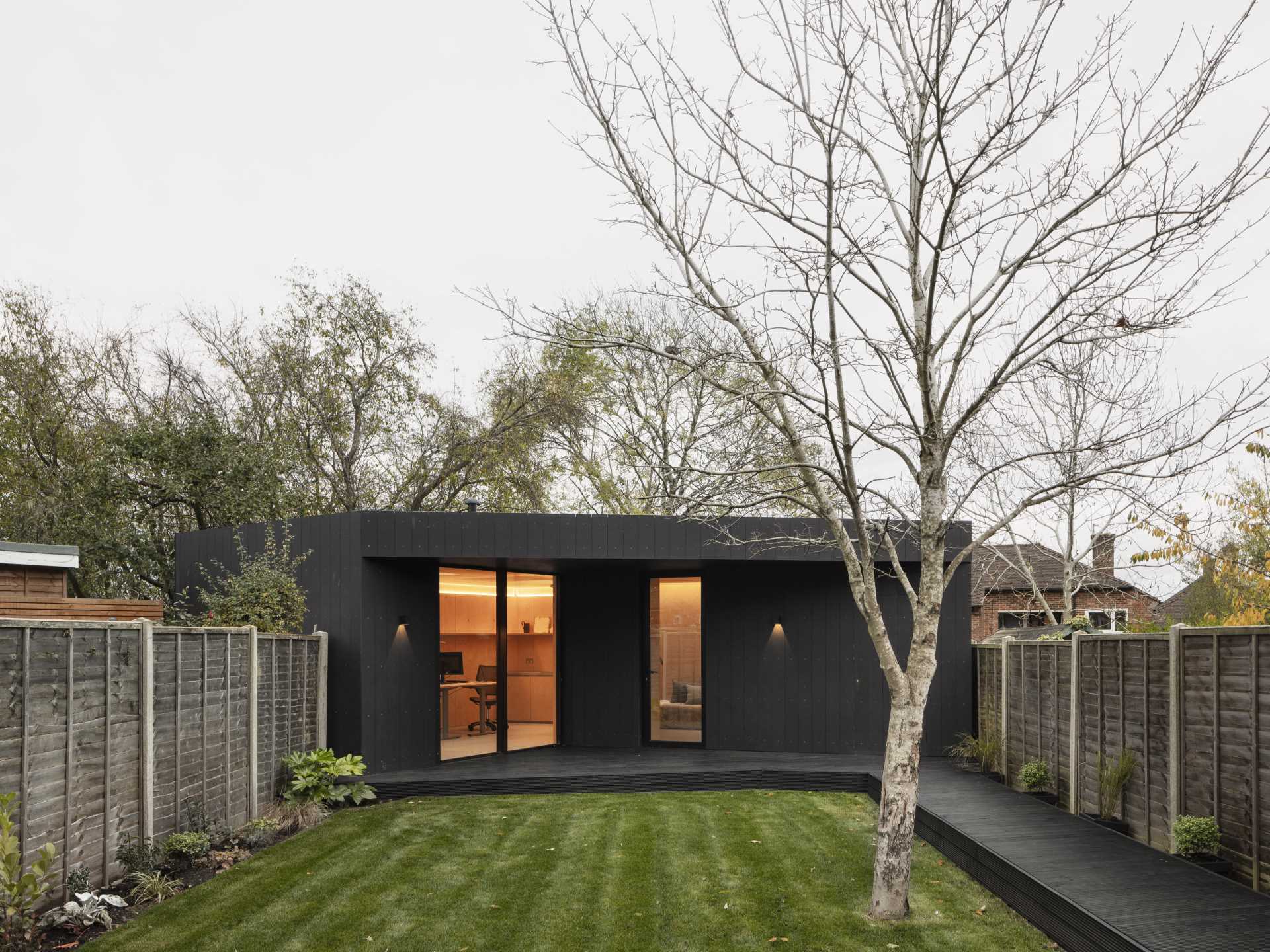 A backyard studio and guest suite has been built with blockwork walls, a timber structure roof, and black fibre-cement cladding.