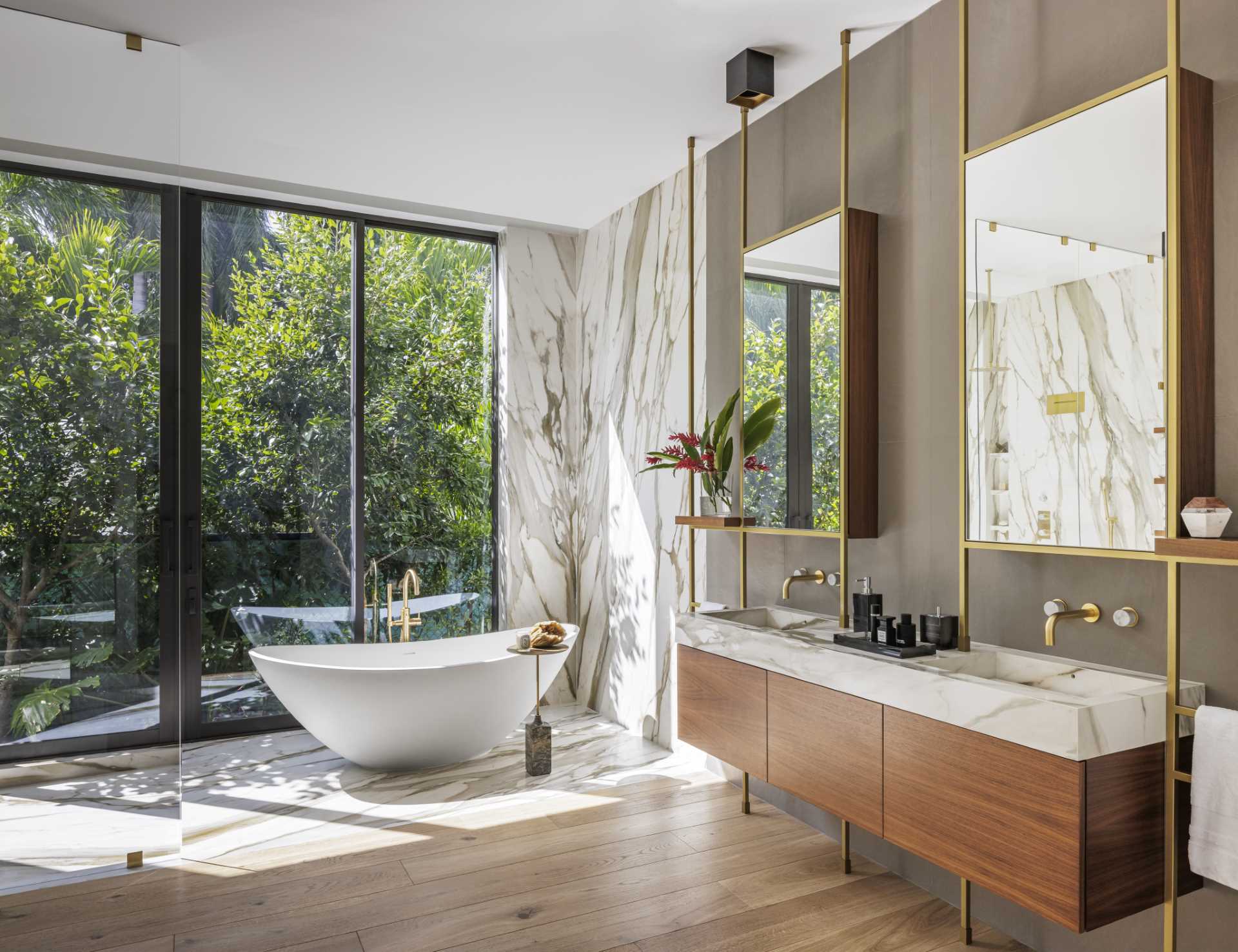 This modern bathroom has a freestanding bathtub by the windows, while the double vanity has a pair of bronze framed mirrors.