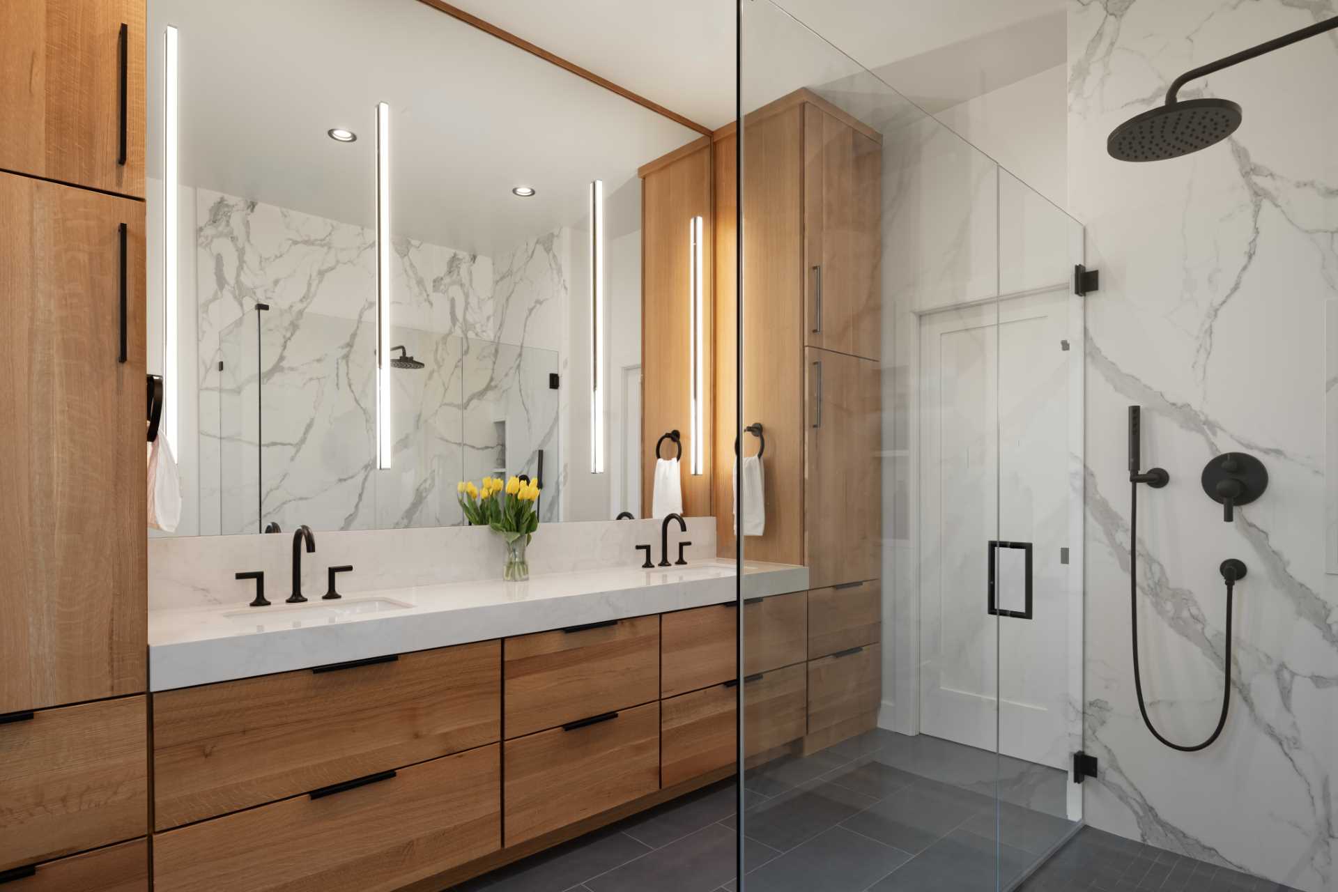 In this modern en-suite bathroom, there's a double vanity with plenty of storage and a walk-in shower with a pair of shelving niches.