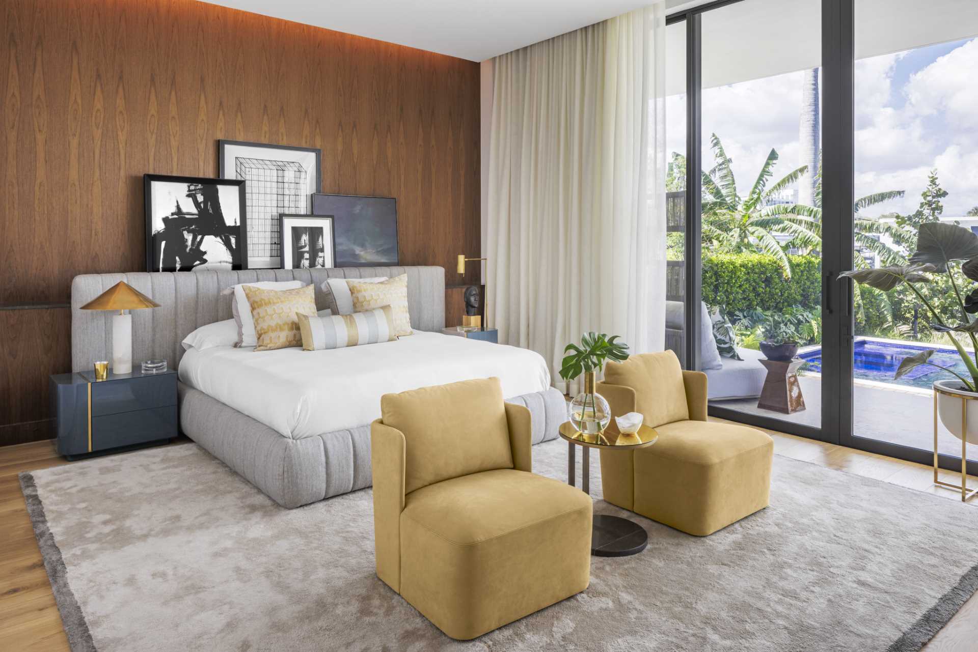 This modern bedroom with a wood accent wall, faces the outdoor scenery through the floor-to-ceiling windows.