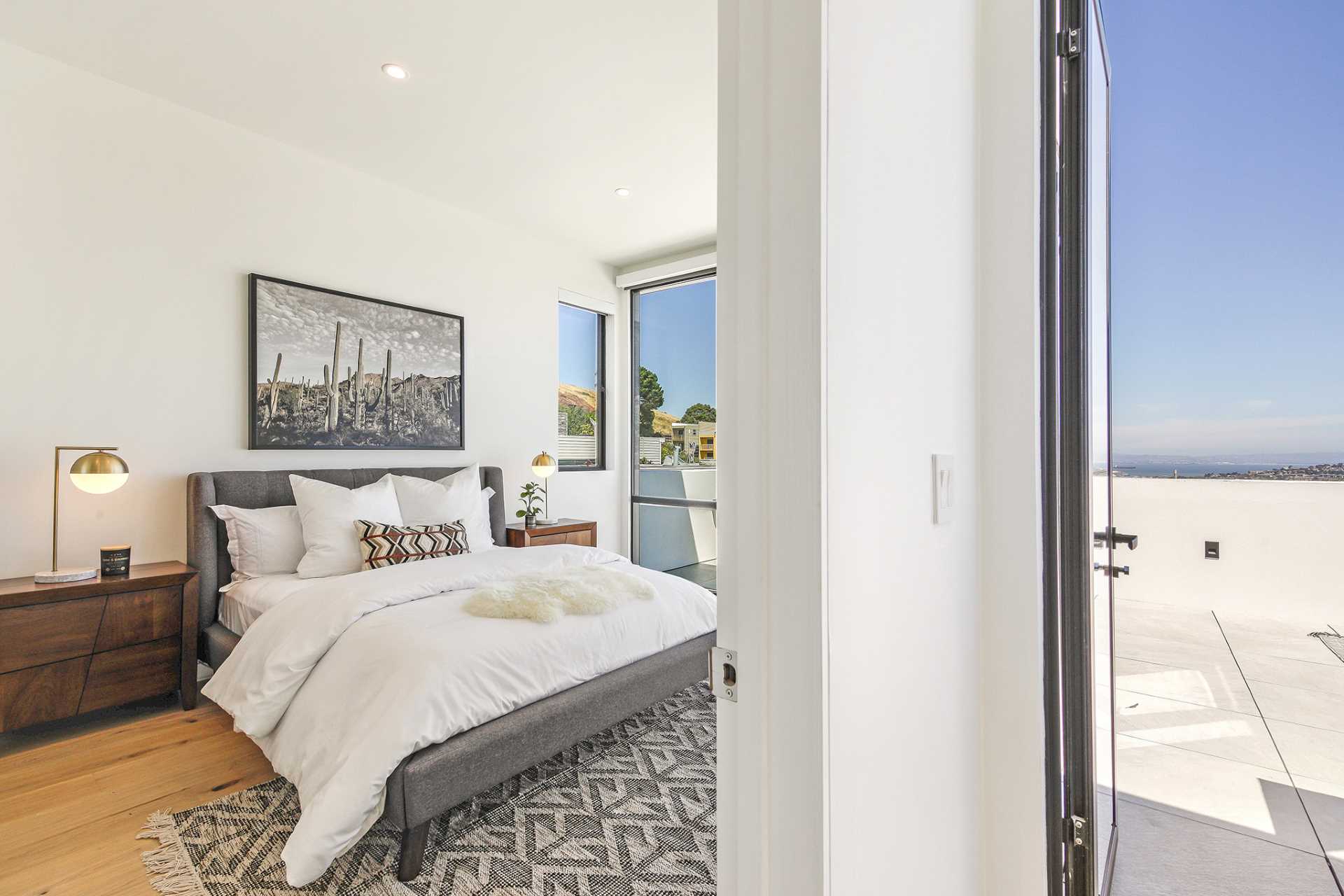 This modern bedroom has floor-to-ceiling windows with a door that opens to a rooftop patio.