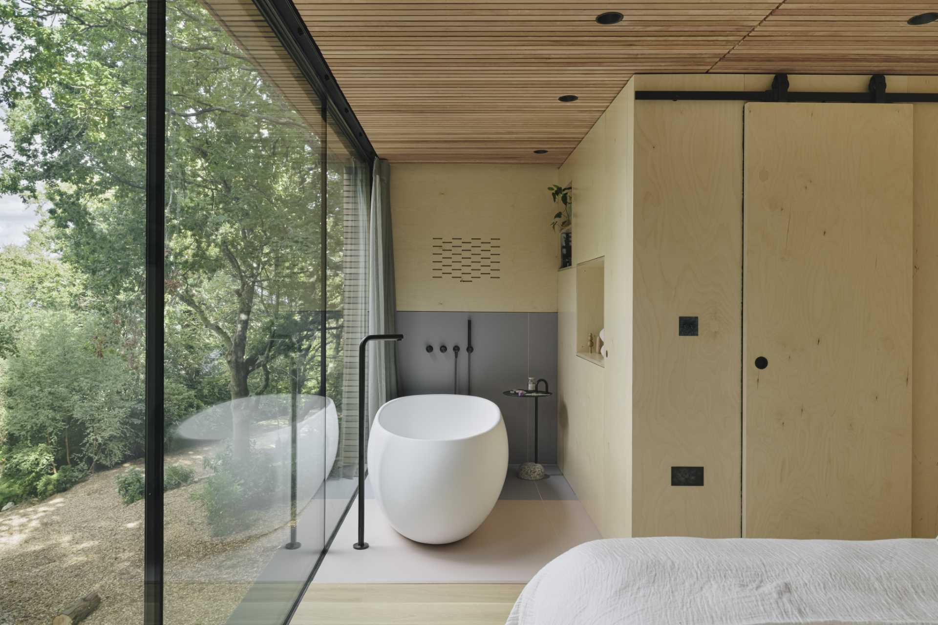 A bedroom with a freestanding bathtub and an en-suite bathroom hidden behind a sliding door.