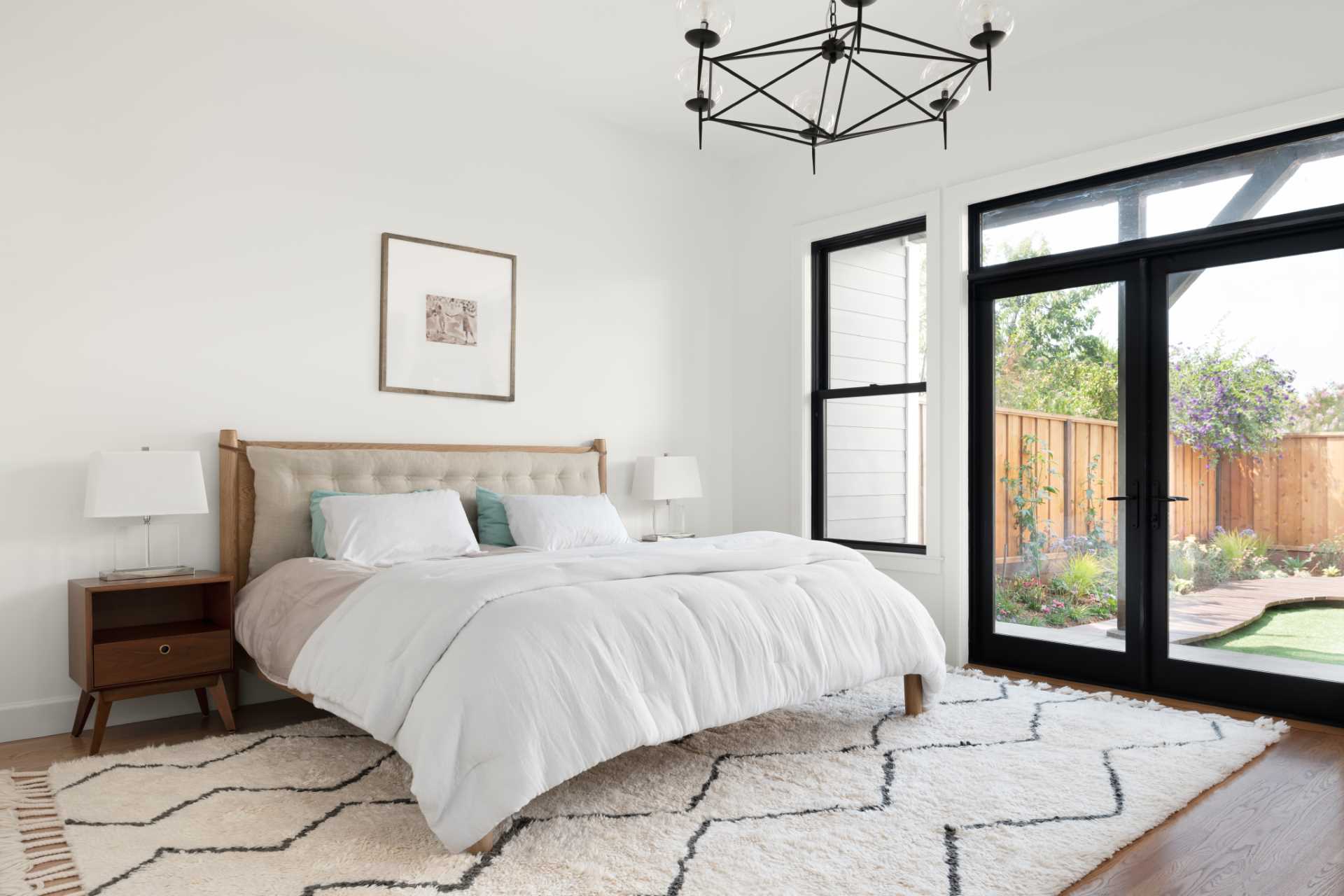 In this modern bedroom, black-framed windows and doors provide a view of the rear yard.