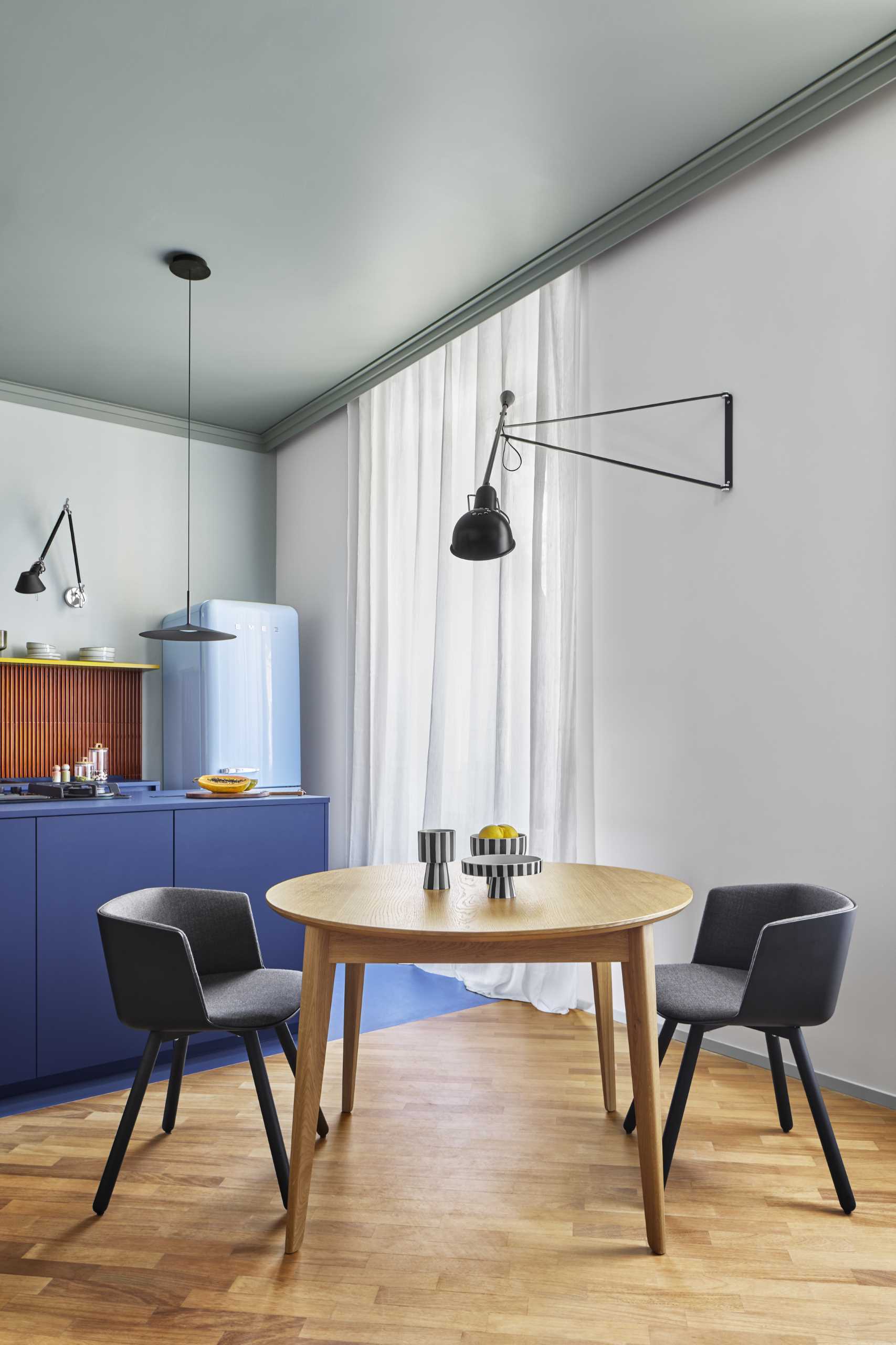 The dining area separates the kitchen from the living room and includes a wall-mounted light fixture.