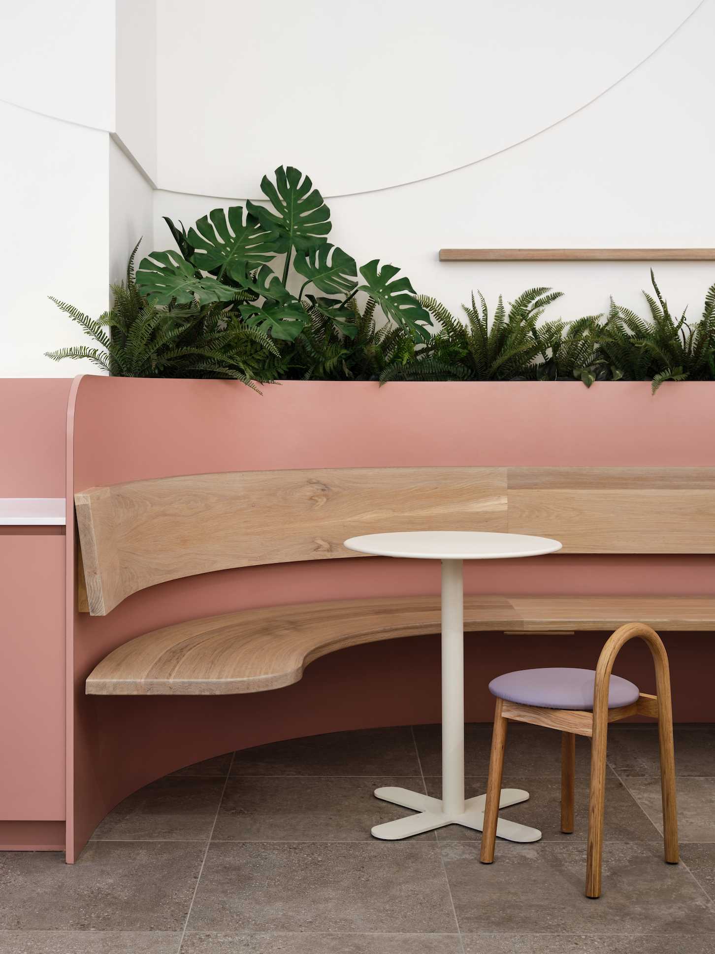 A modern cafe with plants and curved banquette seating.