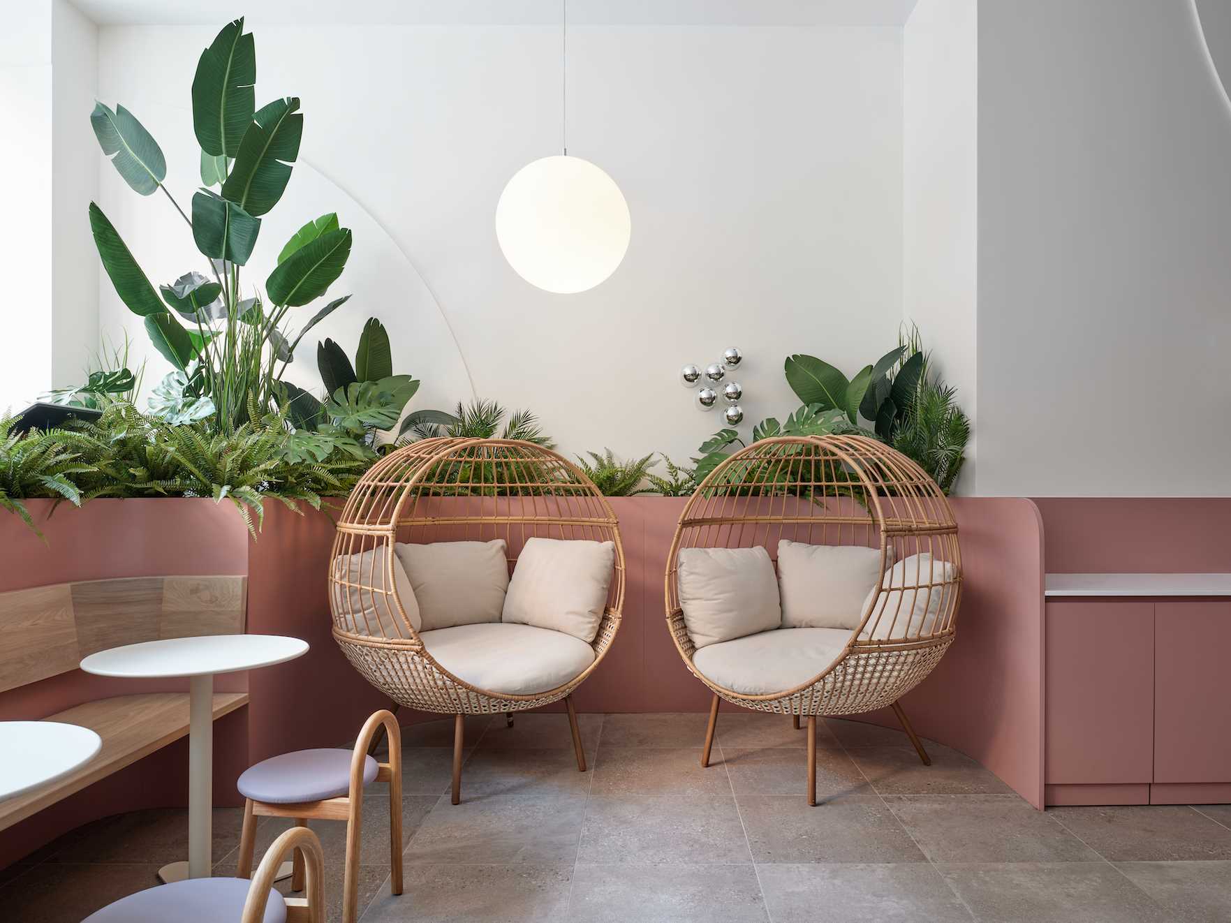 A modern cafe with plants, cozy seating, and soft colors.