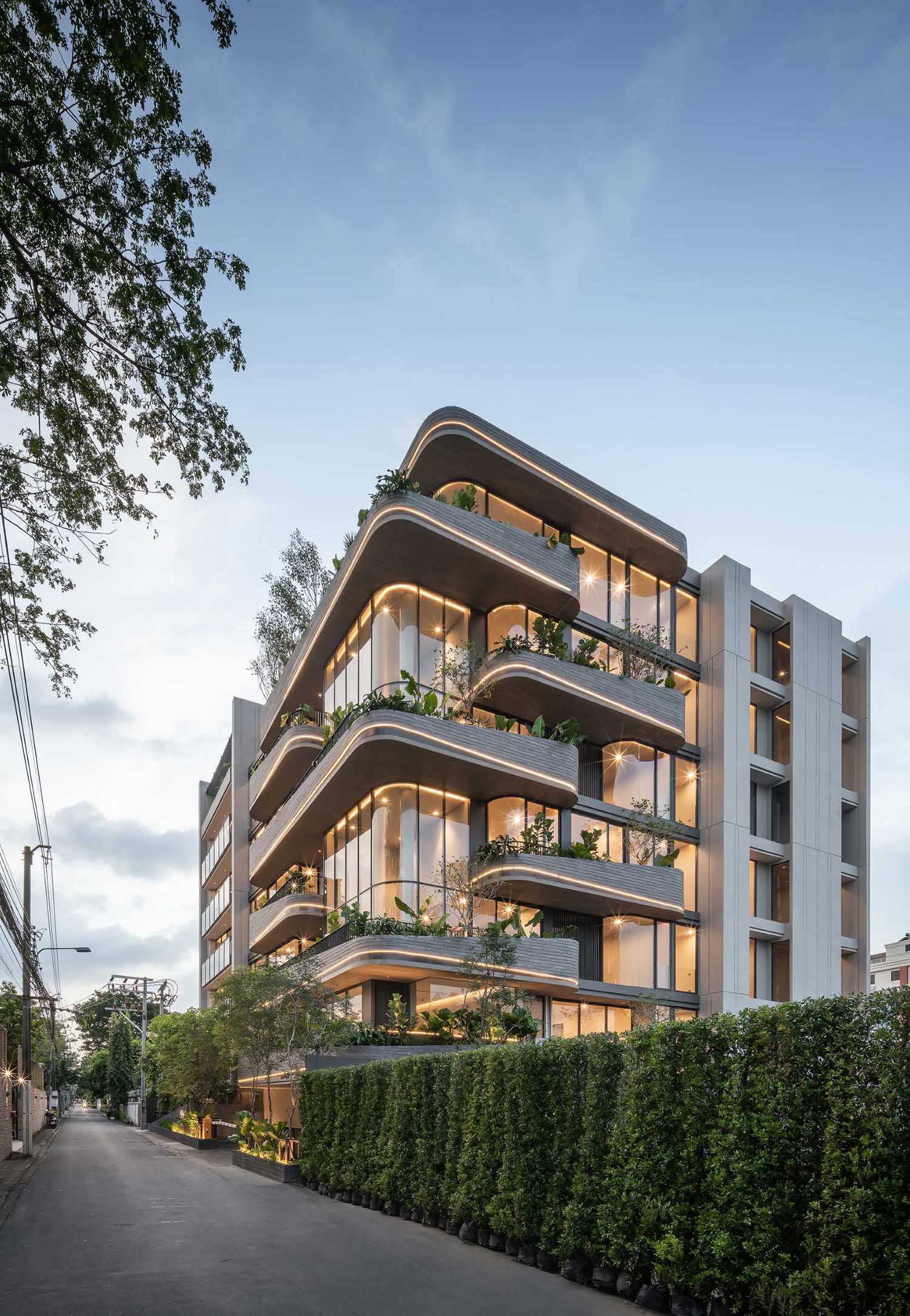 A modern condo building uses lighting to highlight the curves of the exterior.