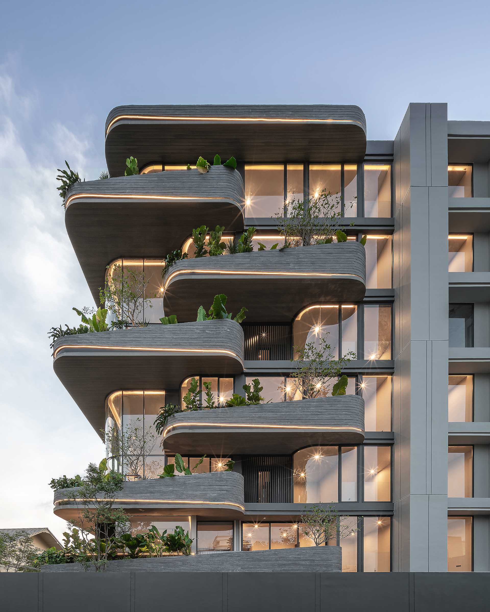 A modern condo building uses lighting to highlight the curves of the exterior.