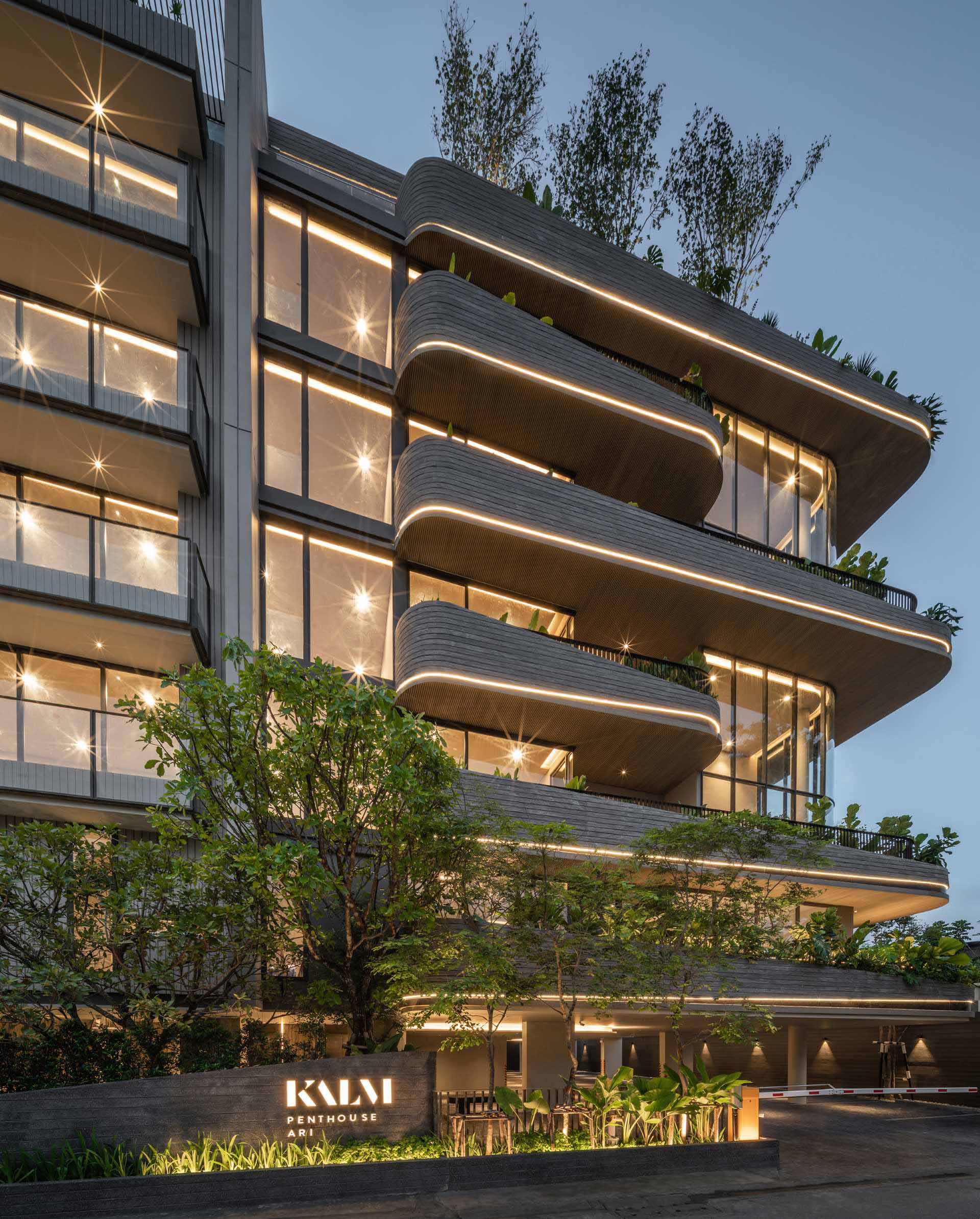 A modern condo building uses lighting to highlight the curves of the exterior.