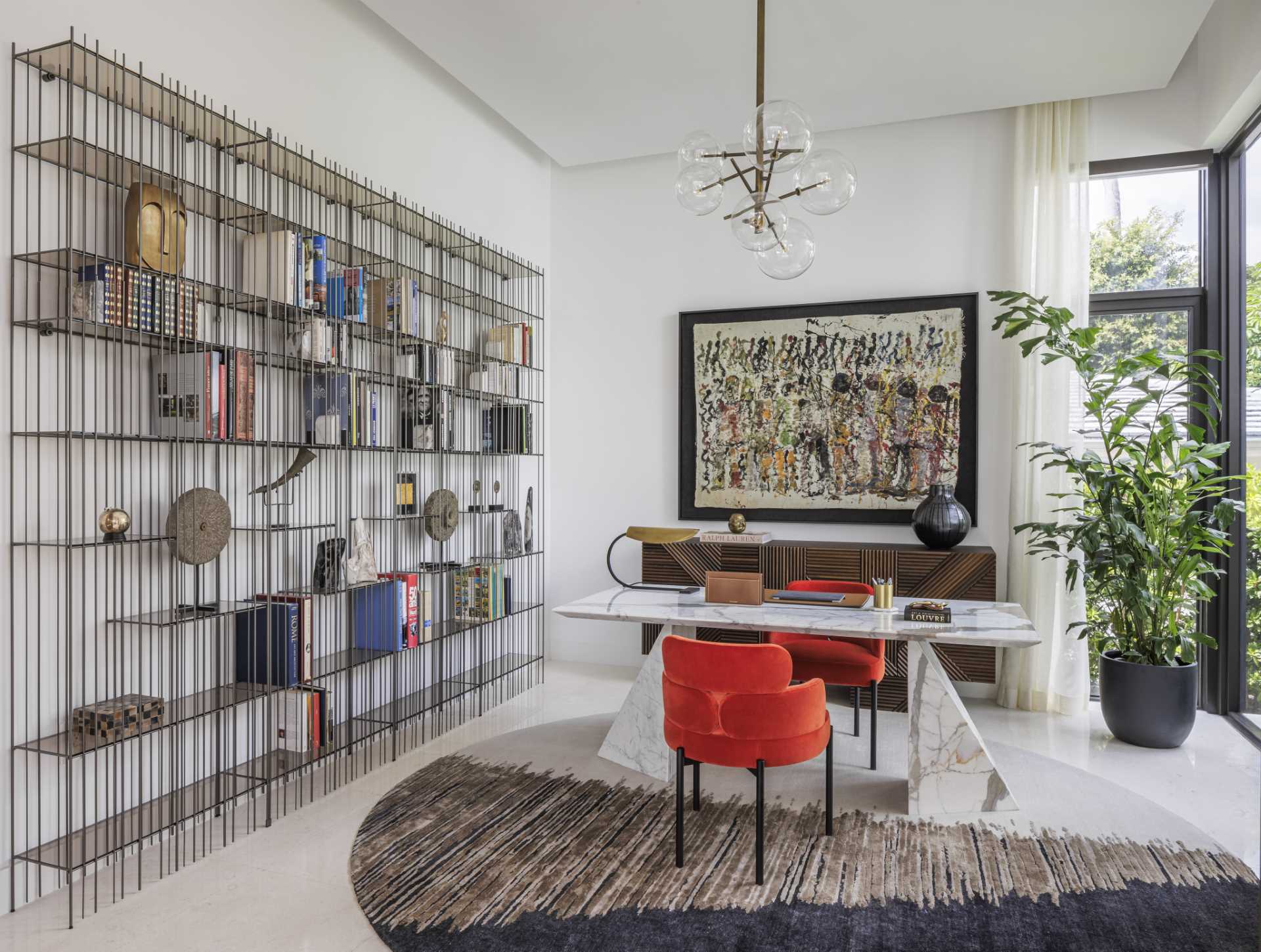 In this home office, there's a desk positioned on a round rug, while the chairs, artwork, and books add color to the room.