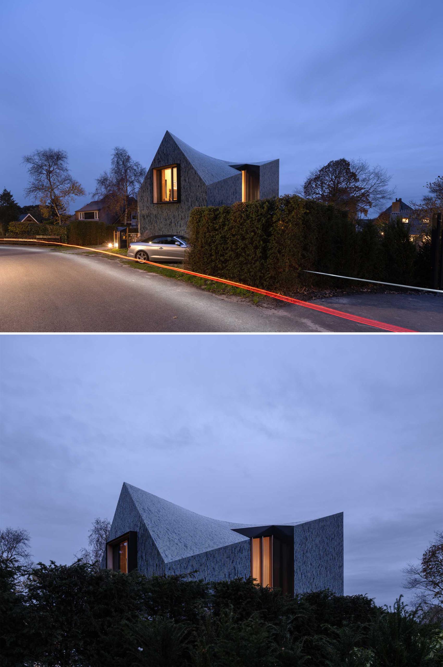 A modern house covered in blue tiles, that also has a twisted roof.