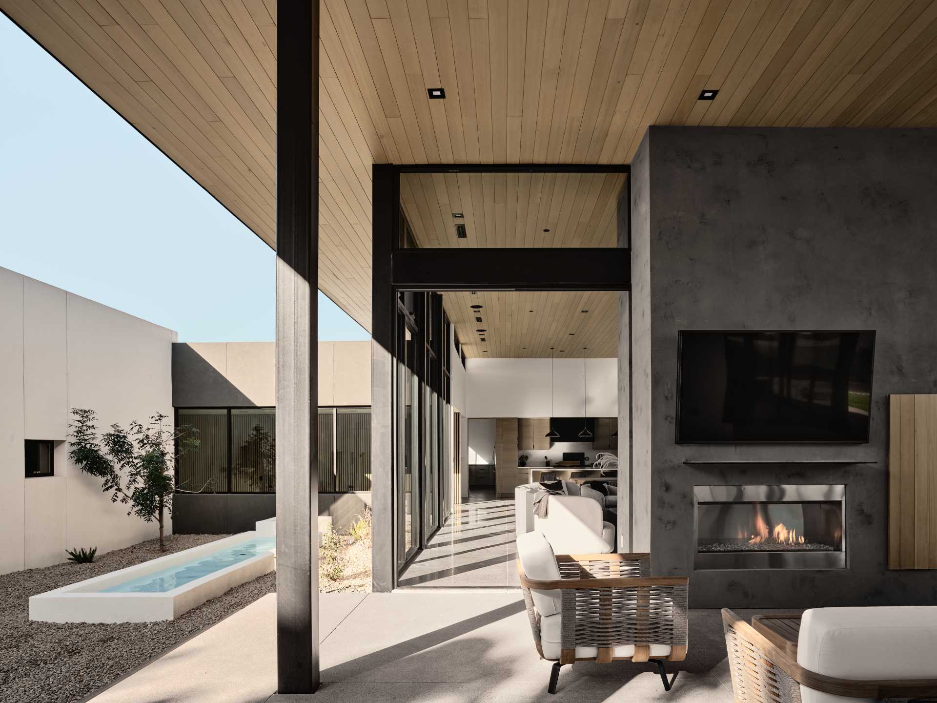 A modern house with a covered outdoor living room, fireplace, and bbq area.