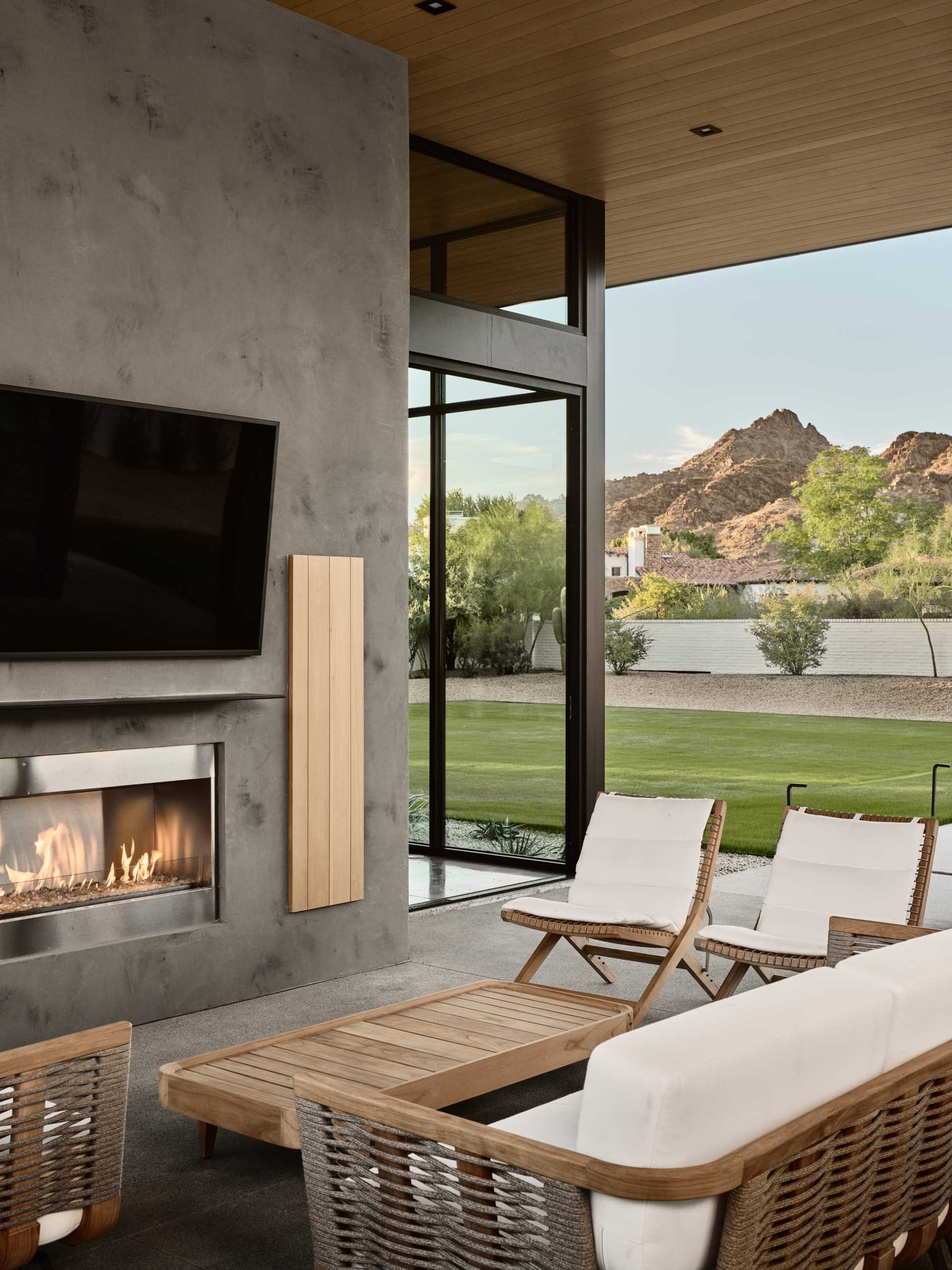 A modern house with a covered outdoor living room, fireplace, and bbq area.