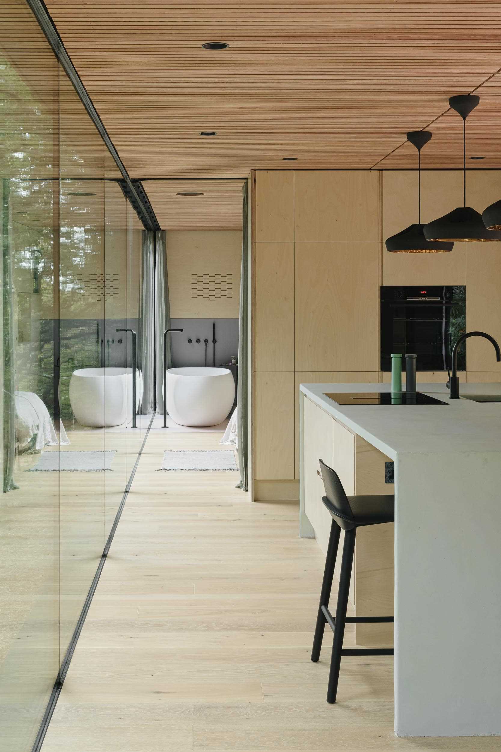 Glass walls and the wood ceiling connect the kitchen to the bedroom.