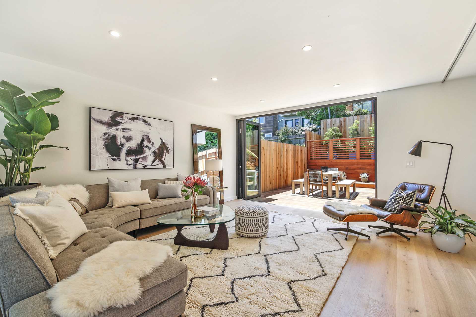 A modern living room with folding glass doors that open to a rear patio.