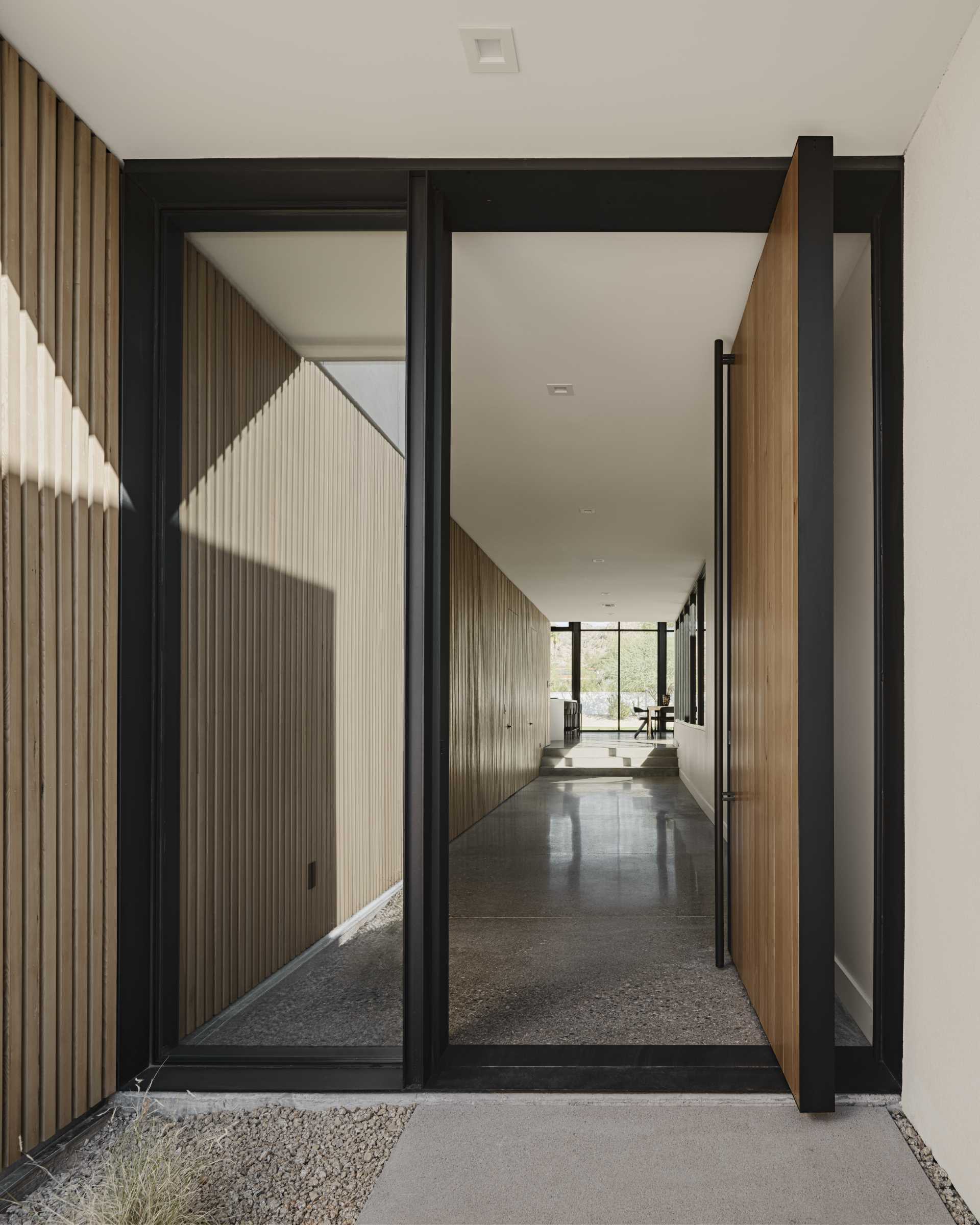 A modern home with a pivoting front door and a wall of Hemlock slats.