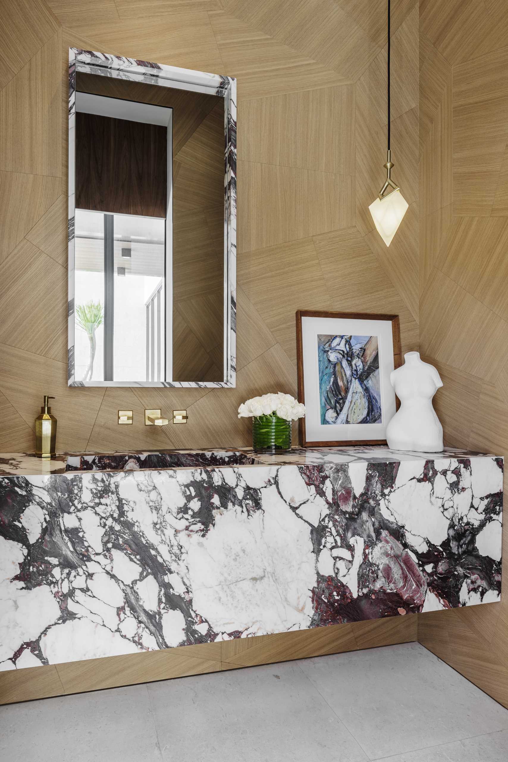 In the powder room, wood walls provide a backdrop for the stone vanity and matching mirror.