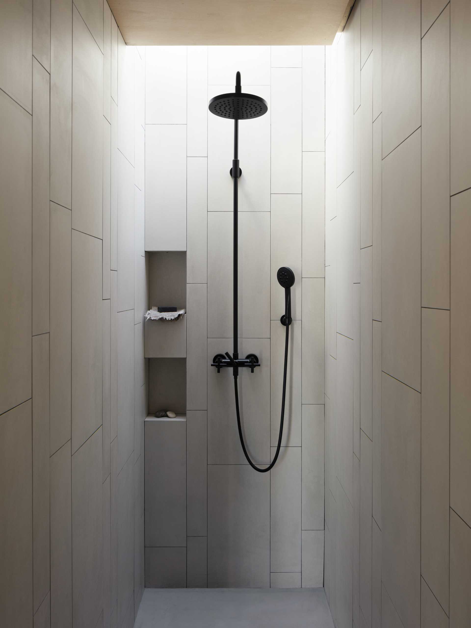 A minimalist grey shower with black hardware and two shelving niches.