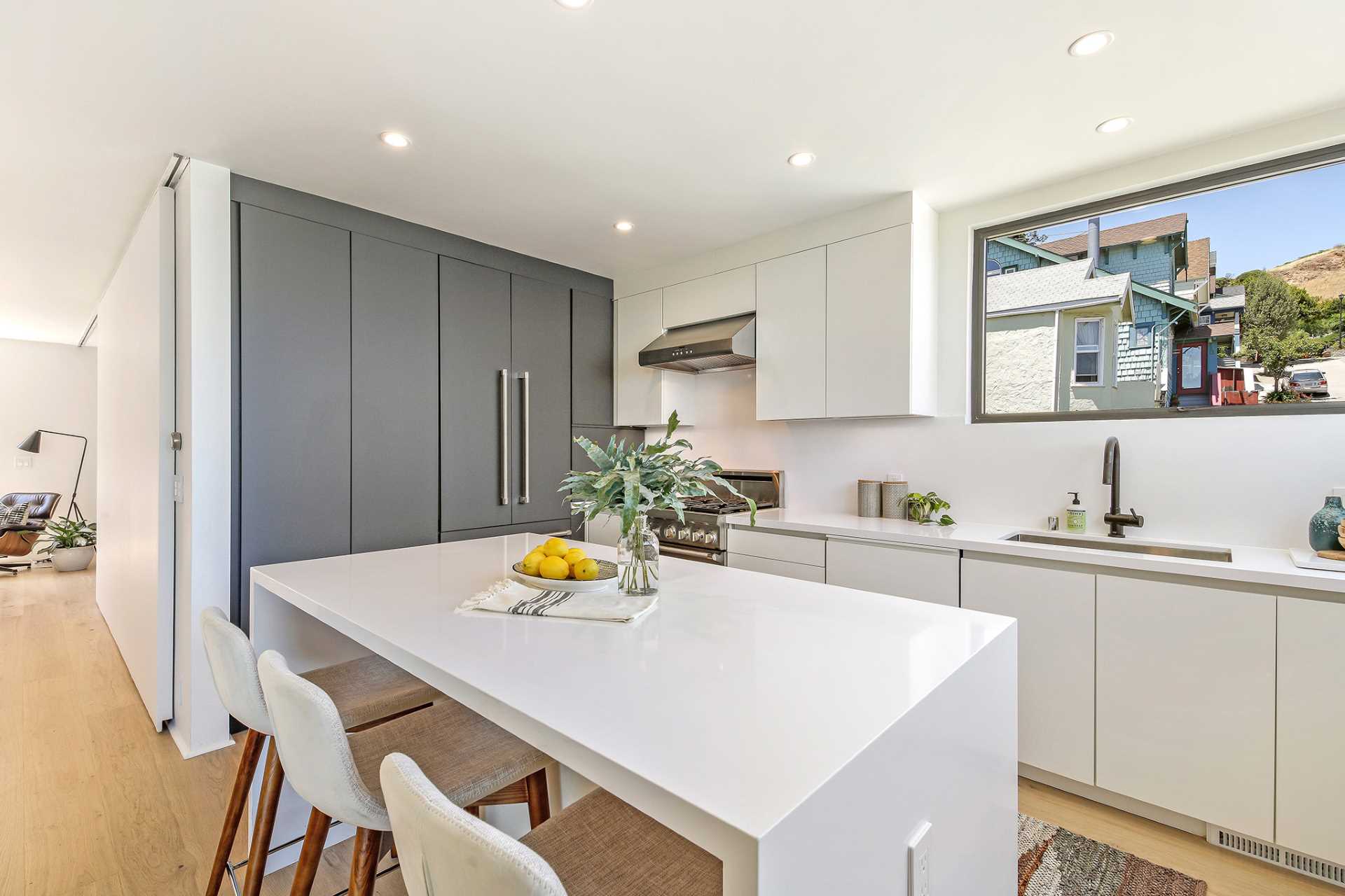 A modern kitchen with white and grey cabinets, and an island with counter height stools.