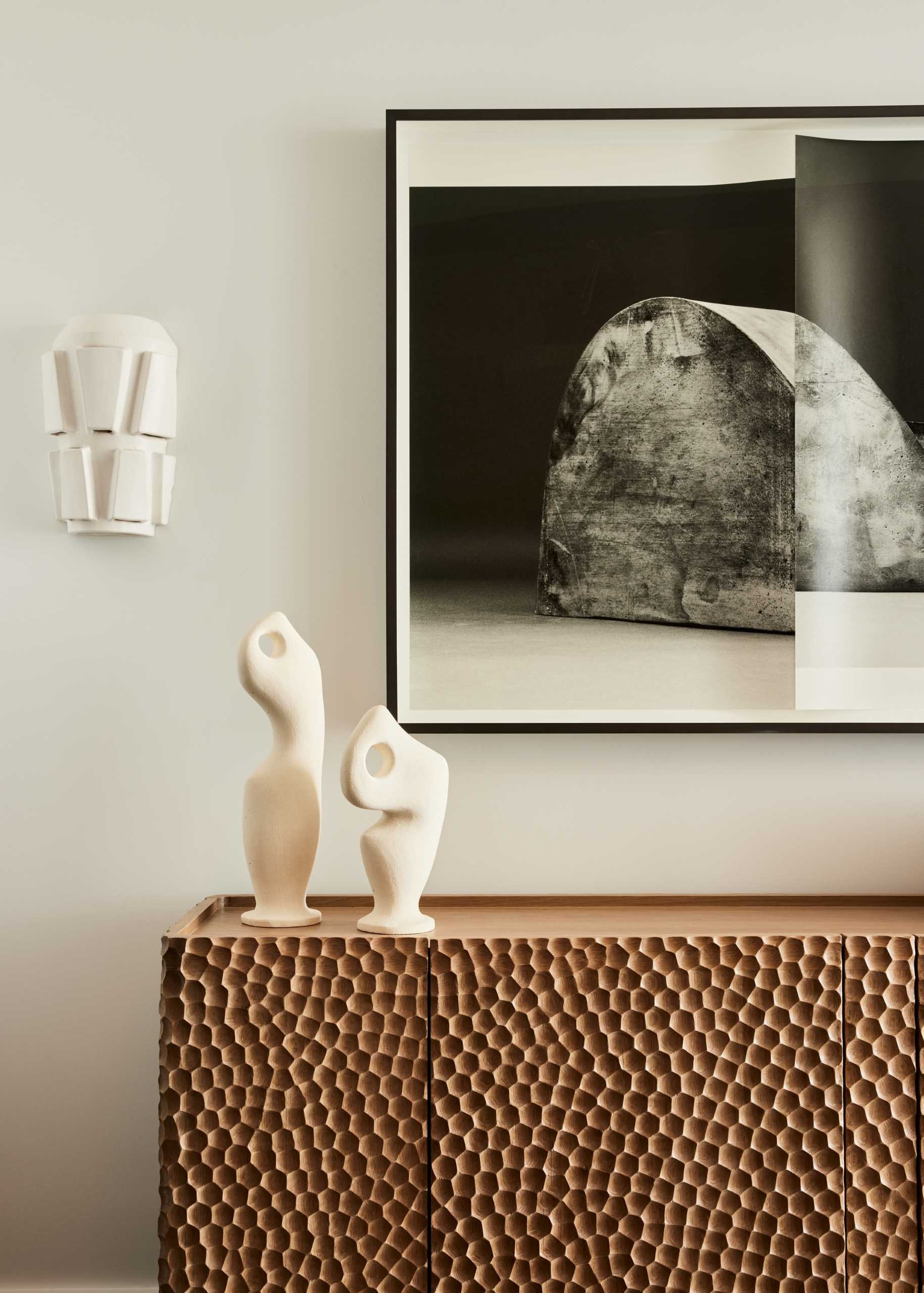 A gouged wood credenza has Erin Schirreff art hanging above and ceramic sconces from The Invisible Collection.