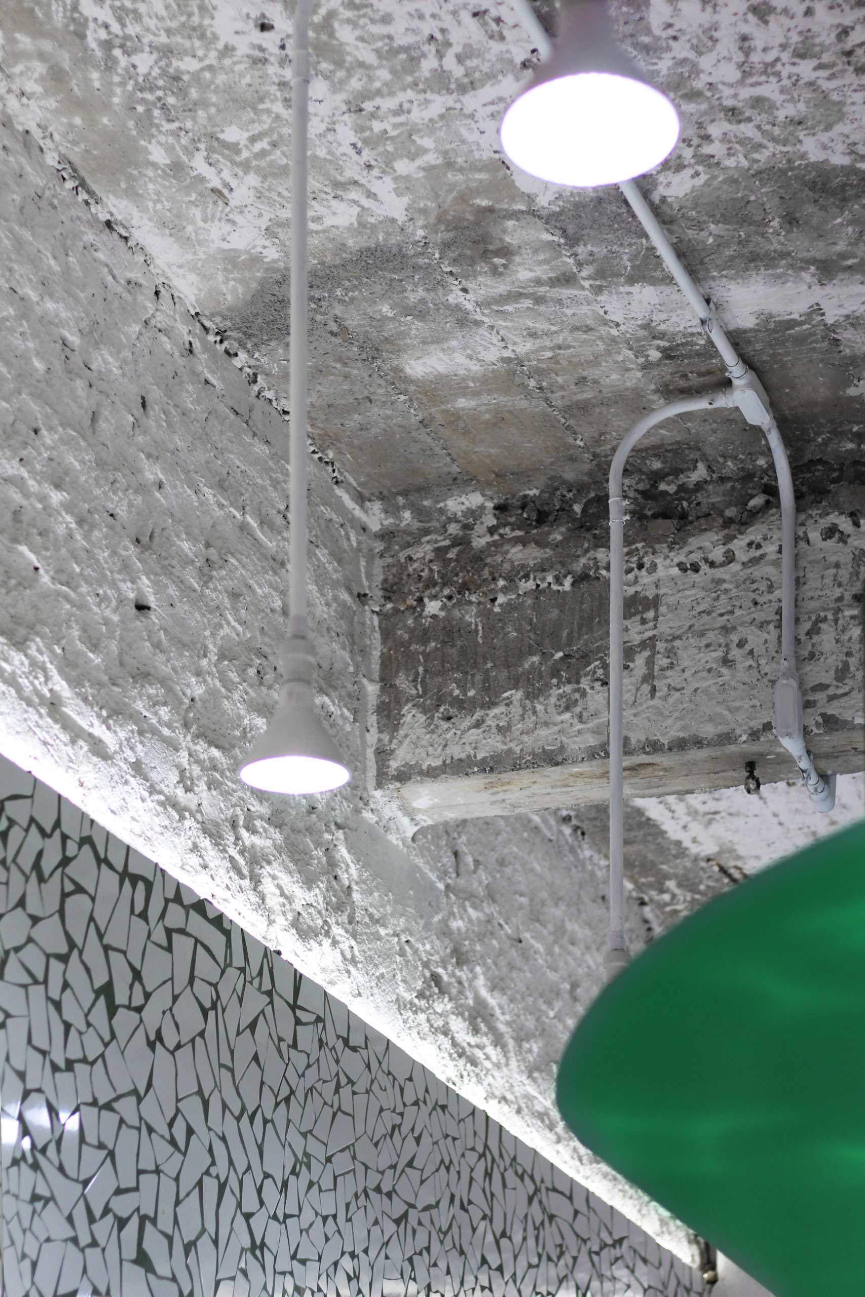 A small taco shop (taqueria) that features broken tile mosaic walls and floor, and a concrete ceiling.