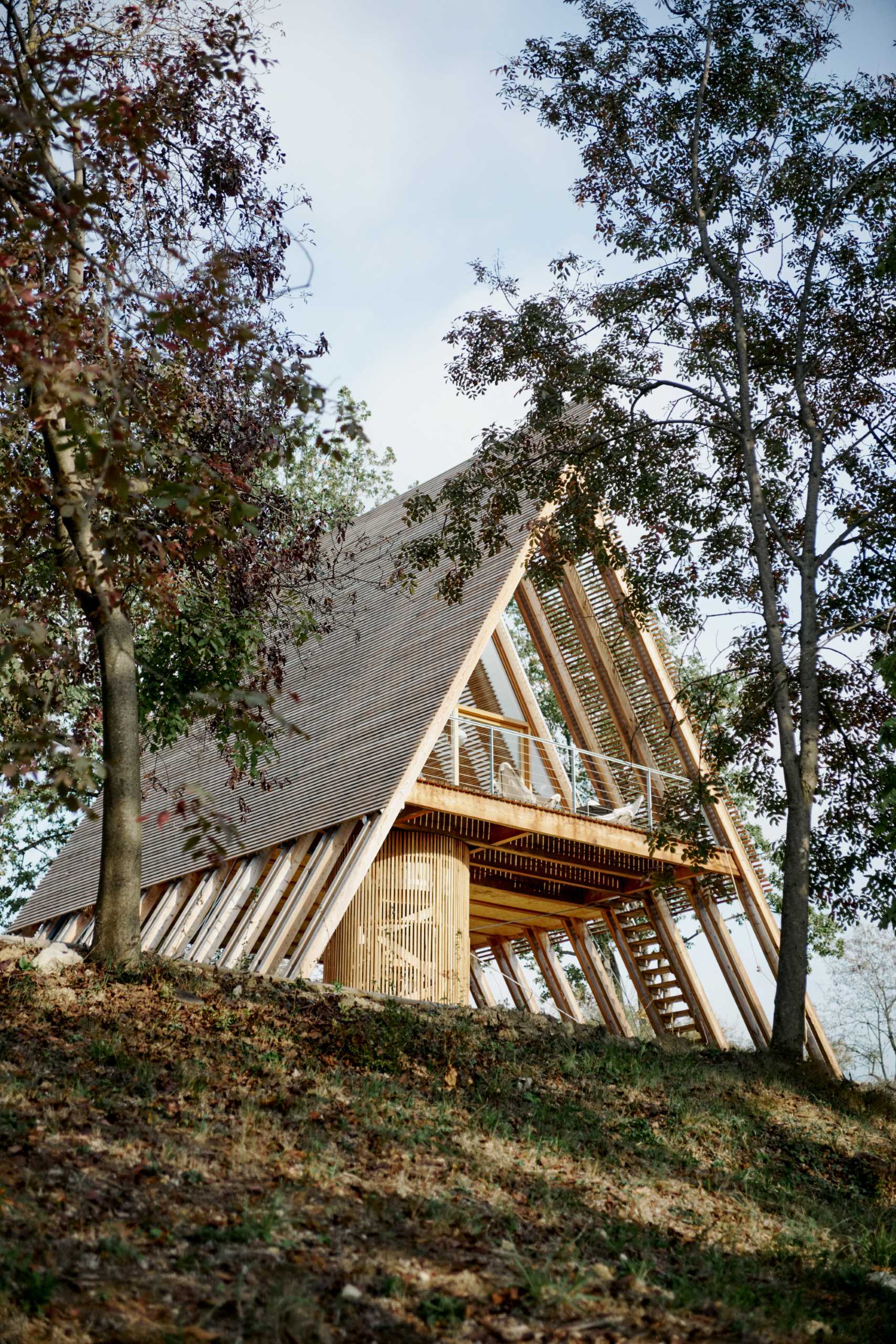 This modern A-frame cabin is raised off the ground, a construction approach that responds to the sloping land of the site.