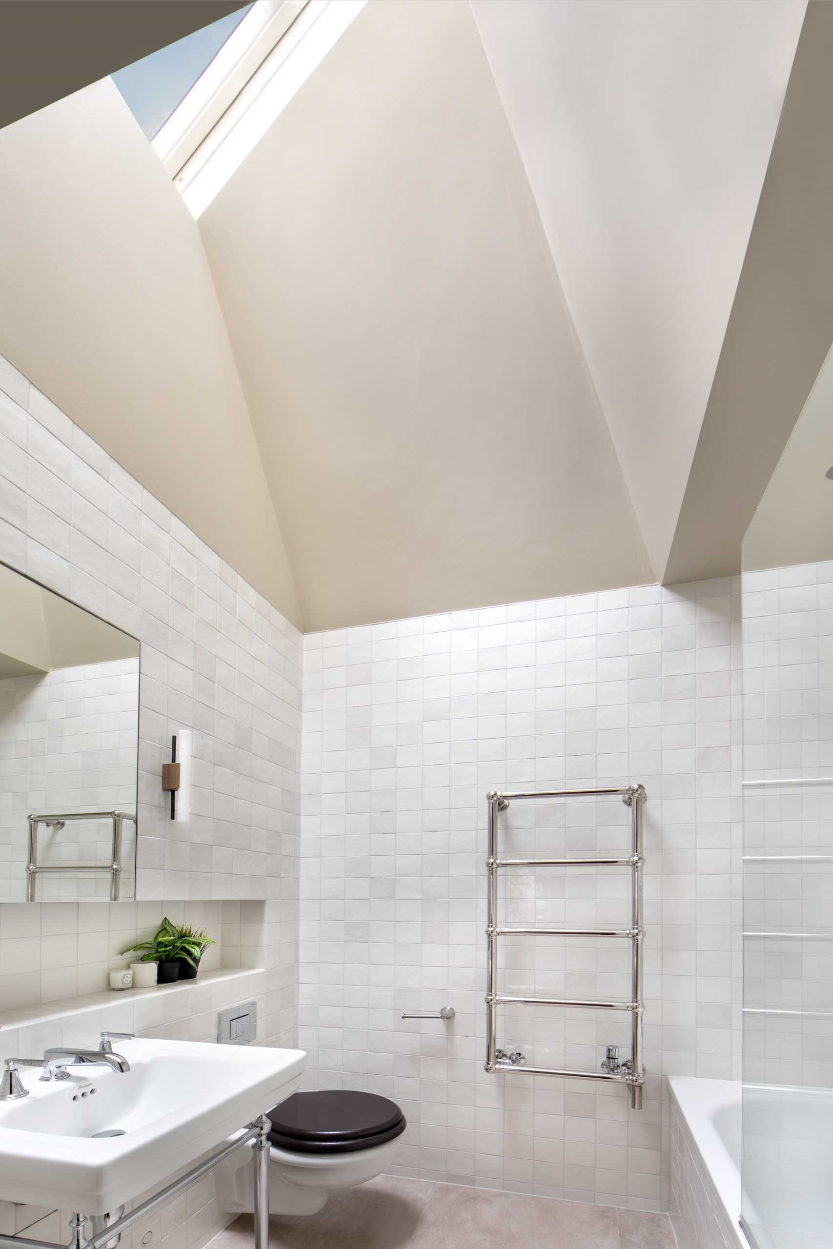 In this contemporary bathroom, square tiles cover the walls, a shelving niche adds storage, and a skylight adds natural light.