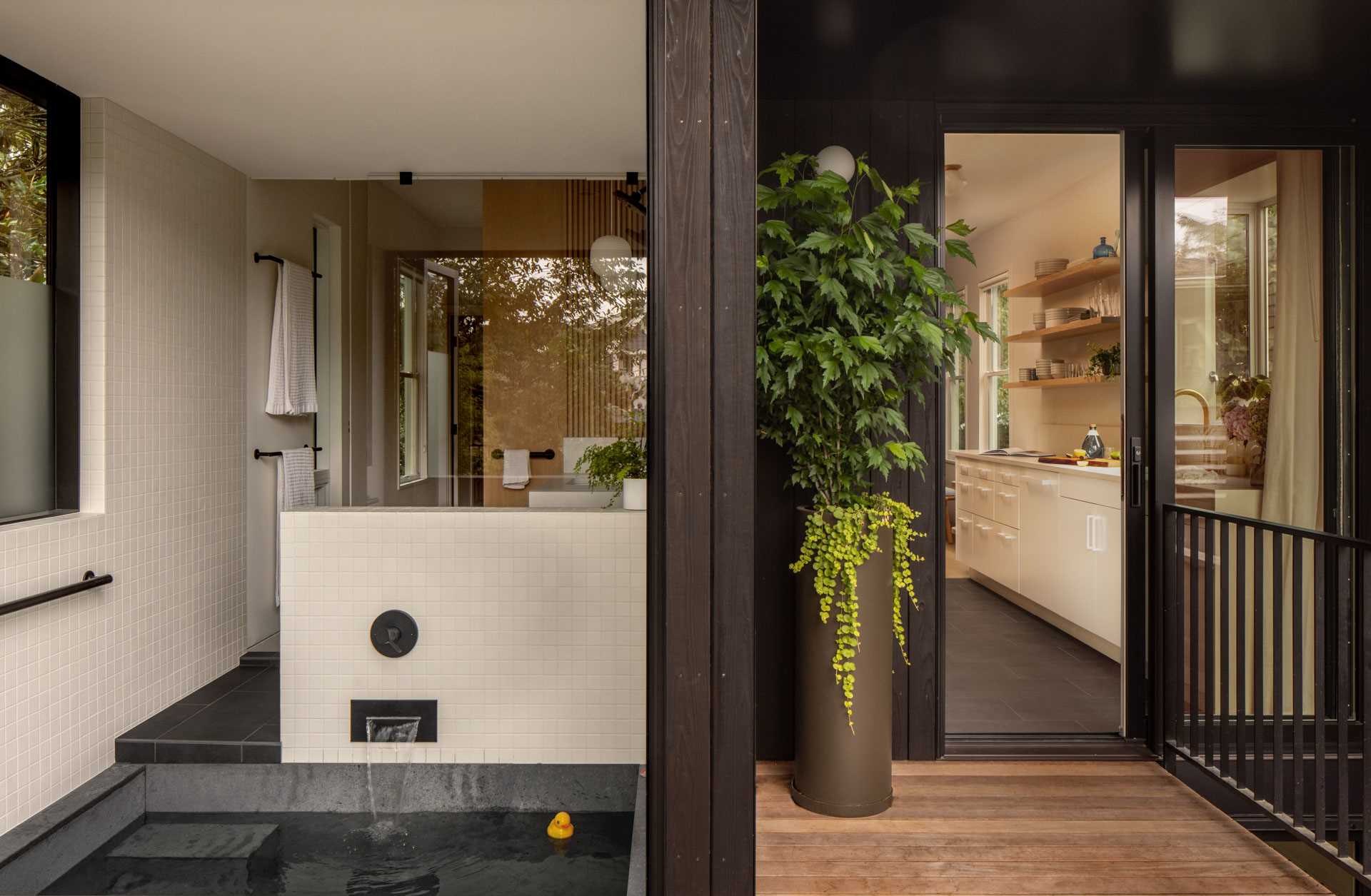 A modern family bathroom includes a traditional Japanese soaking tub (Ofuro), directly connecting to the outdoors via a folding glass door. A separate toilet room increases comfort and usability for the young family.